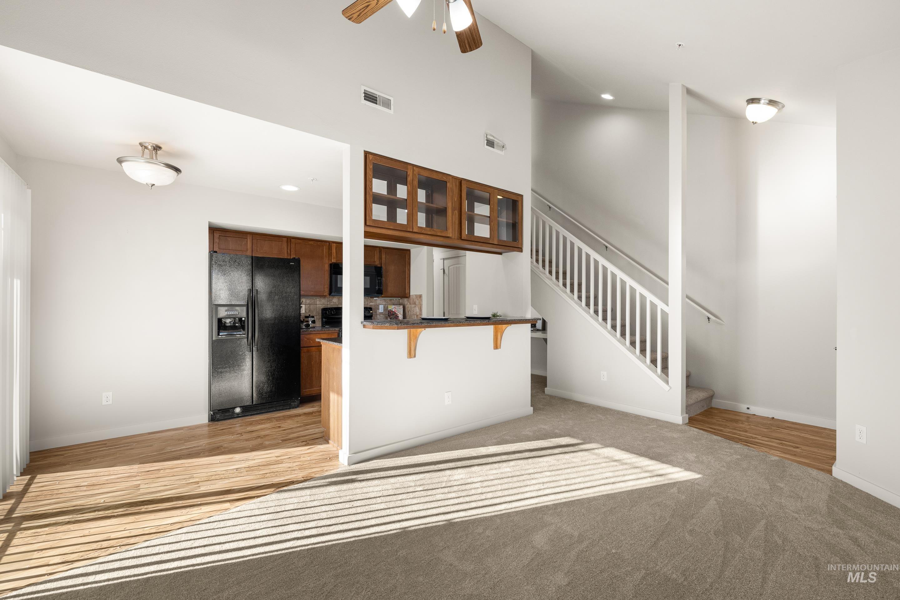 Unfurnished living room with ceiling fan, light carpet, vaulted ceiling, and recessed lighting