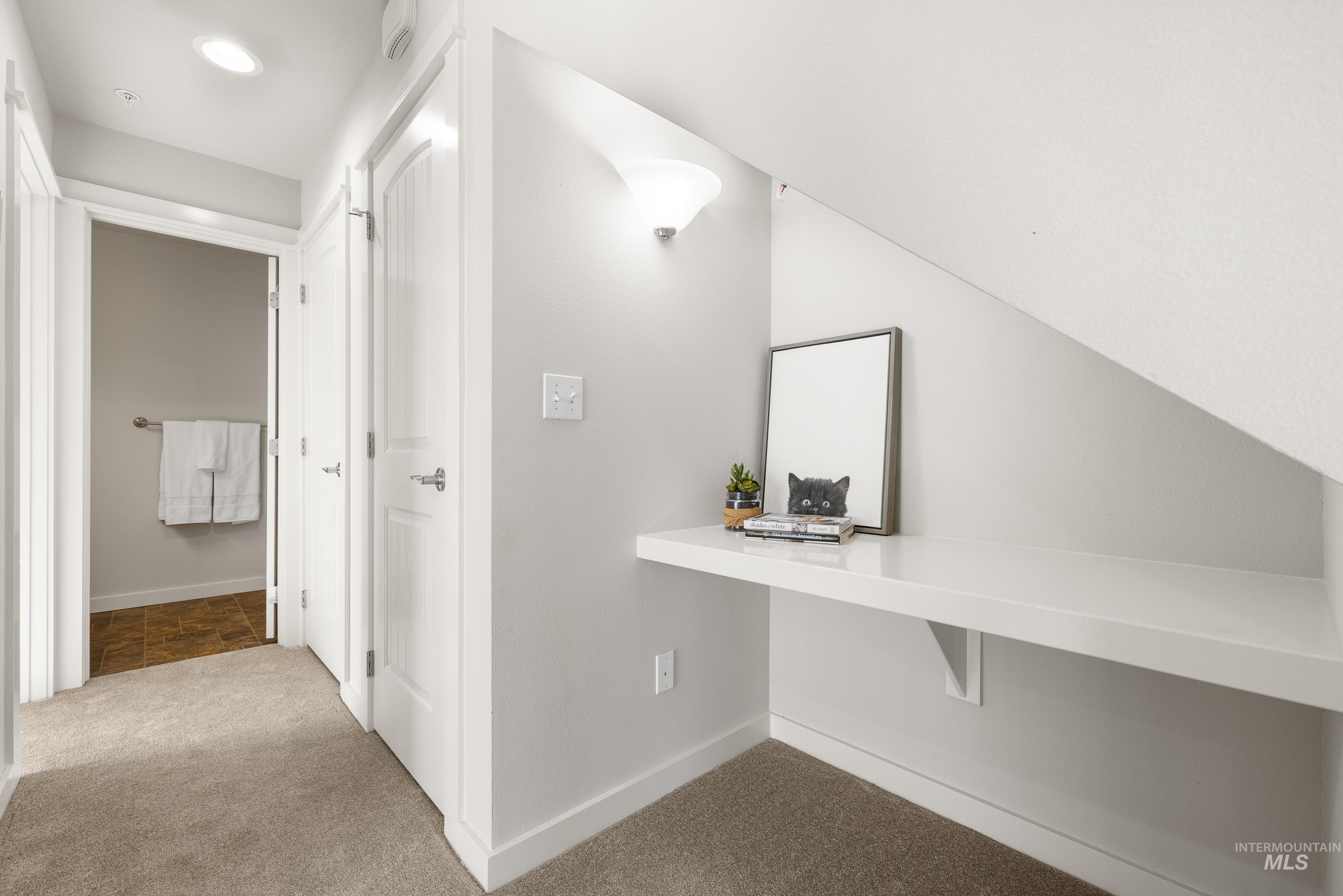Hallway with light colored carpet and baseboards