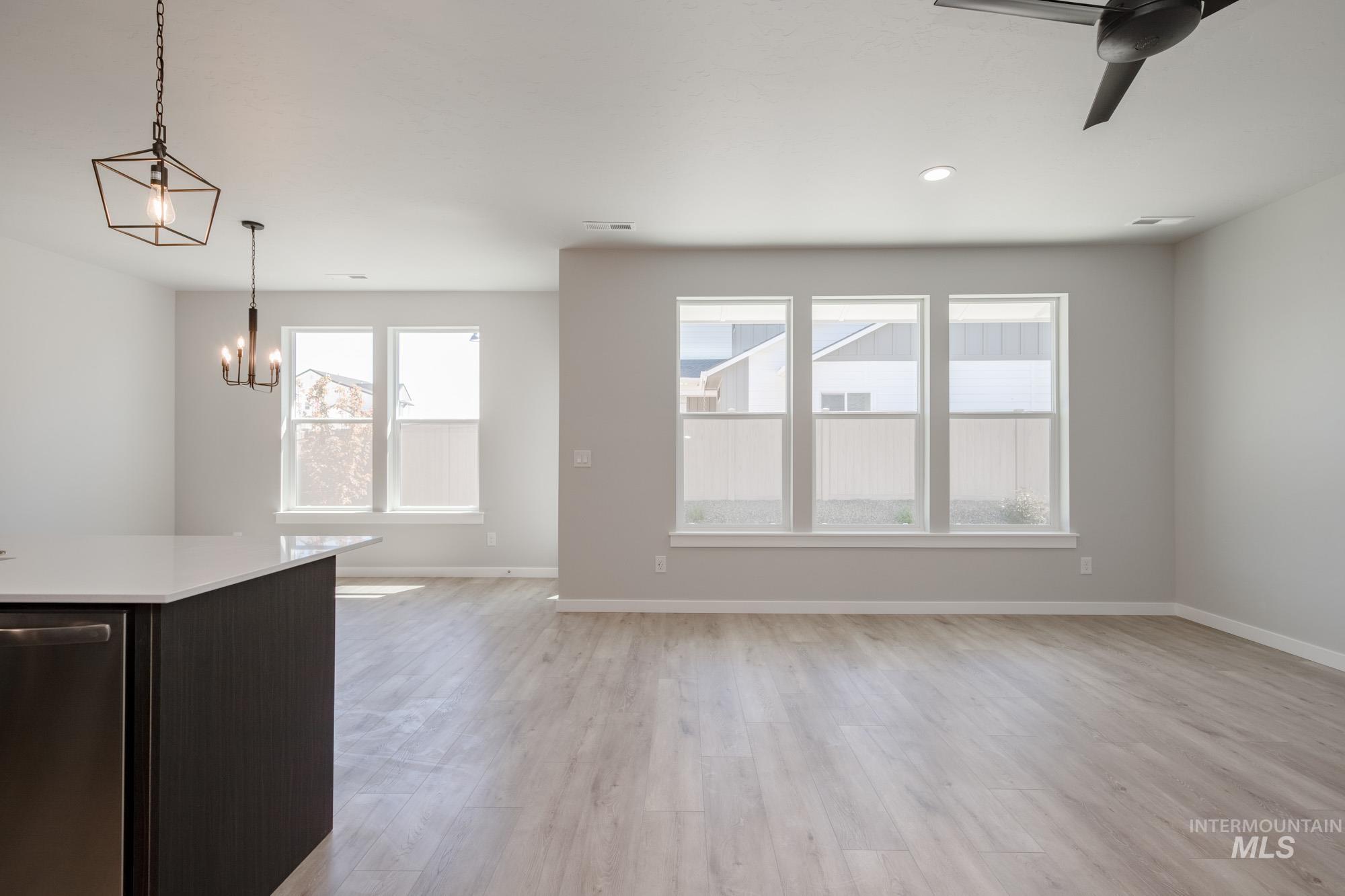 Unfurnished living room featuring light wood-style floors, a chandelier, and a ceiling fan