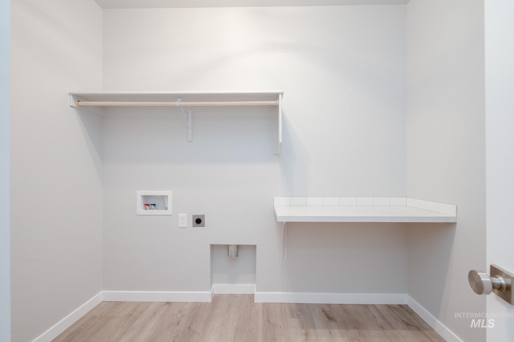 Laundry area with hookup for an electric dryer, wood finished floors, and hookup for a washing machine