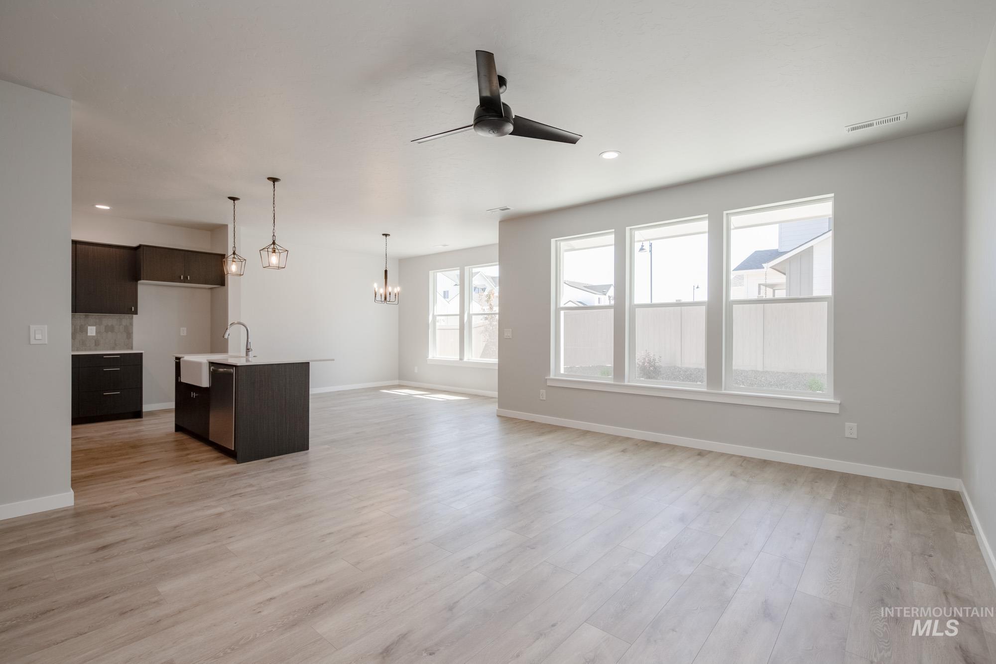 Unfurnished living room featuring a ceiling fan, a chandelier, light wood-style floors, and recessed lighting