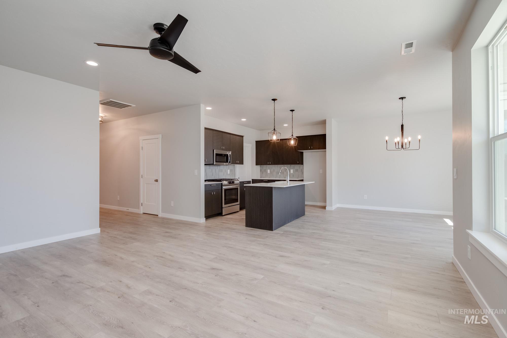 Kitchen featuring open floor plan, stainless steel appliances, dark brown cabinetry, a chandelier, and recessed lighting