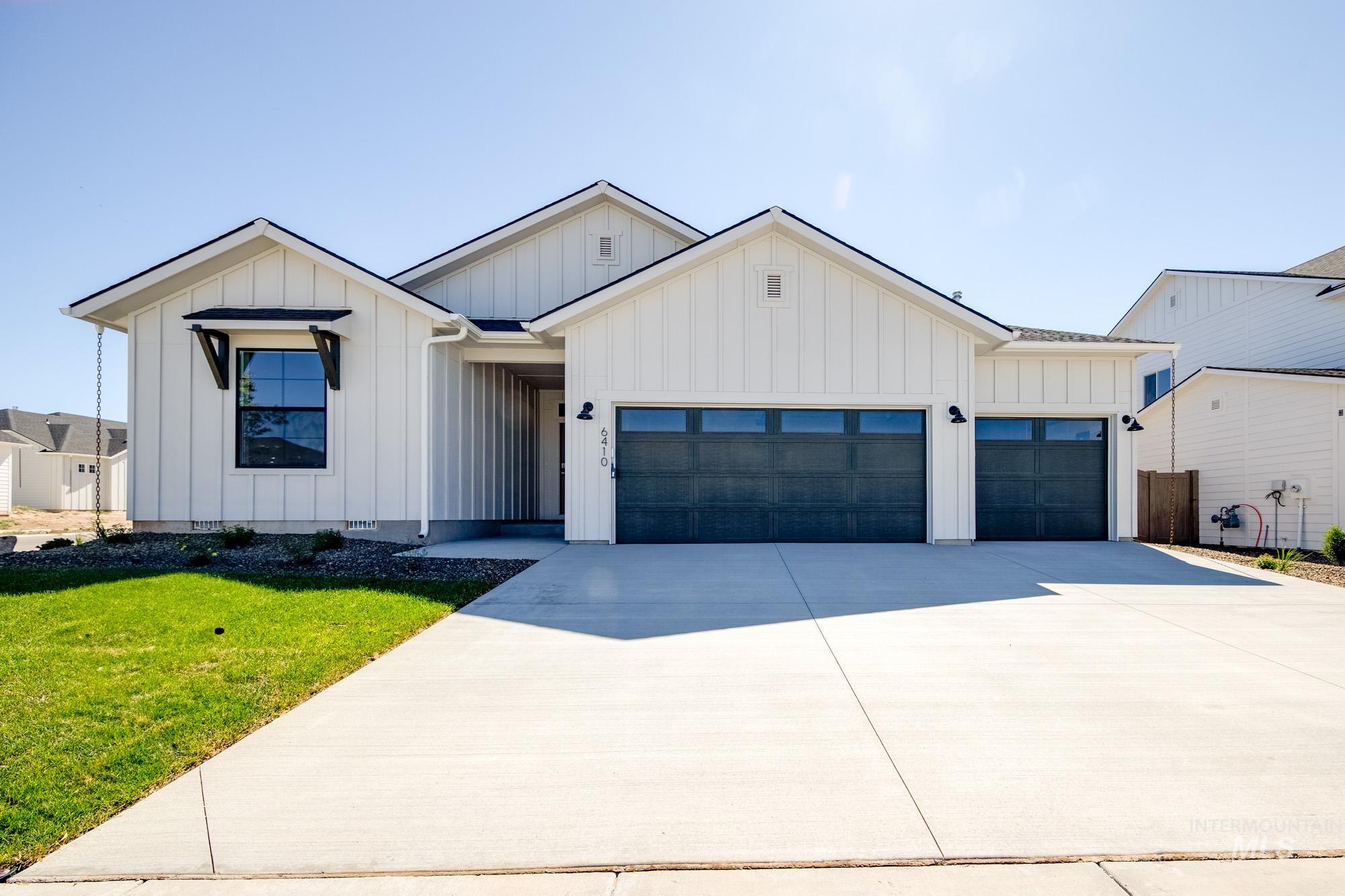 Modern farmhouse style home featuring board and batten siding, a garage, a front lawn, and driveway