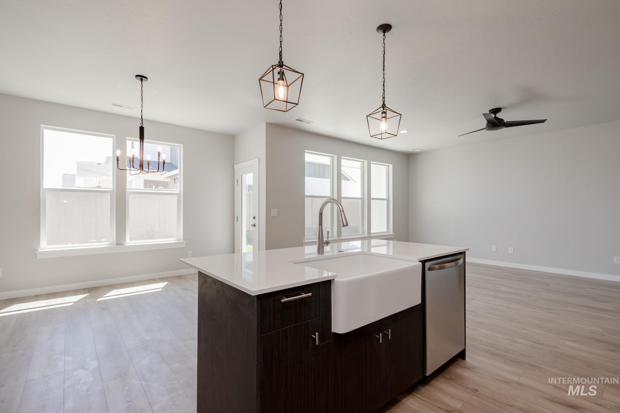 Kitchen featuring dishwasher, open floor plan, light countertops, and light wood-style floors
