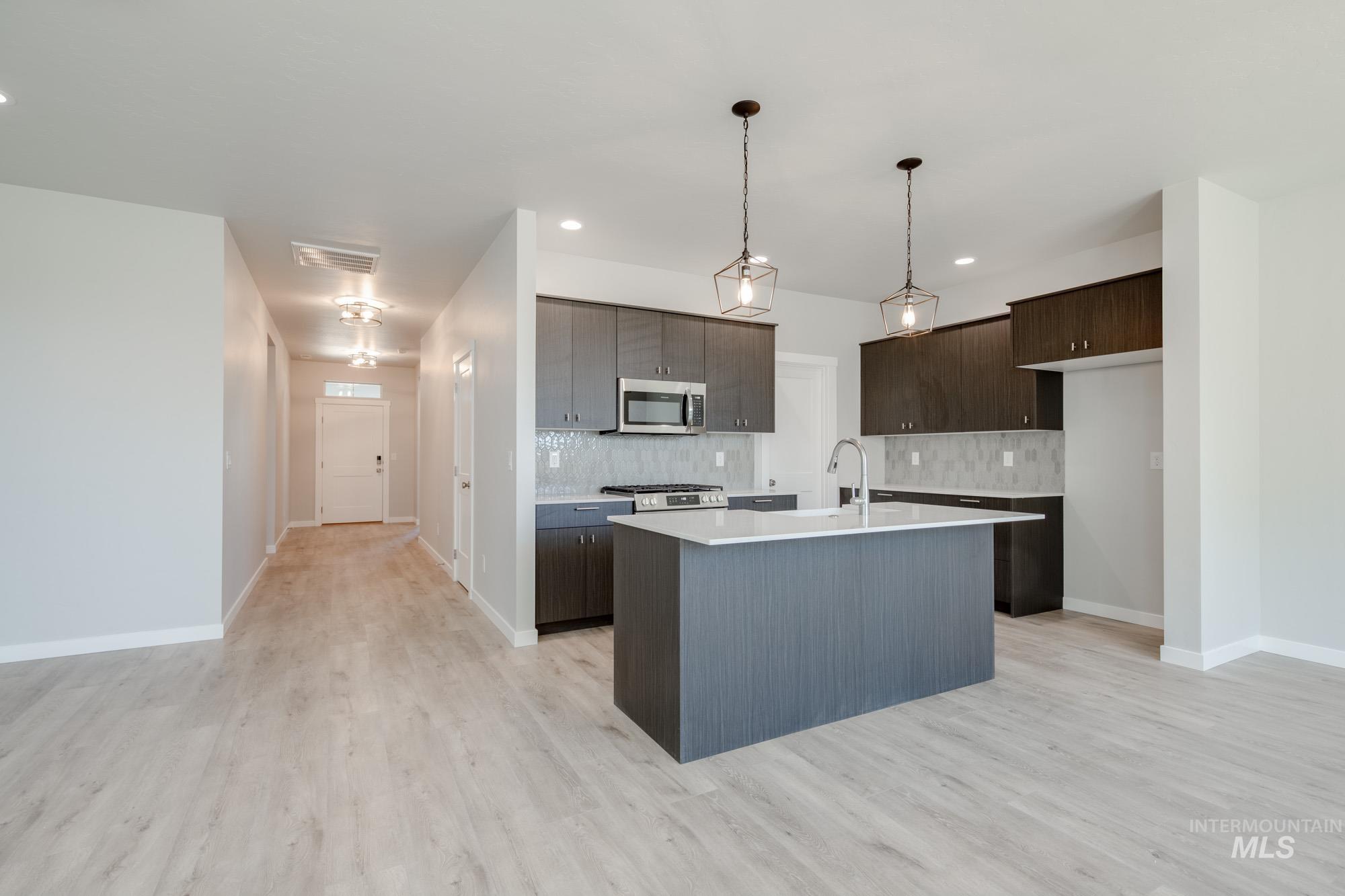 Kitchen with stainless steel microwave, tasteful backsplash, light countertops, dark brown cabinetry, and recessed lighting