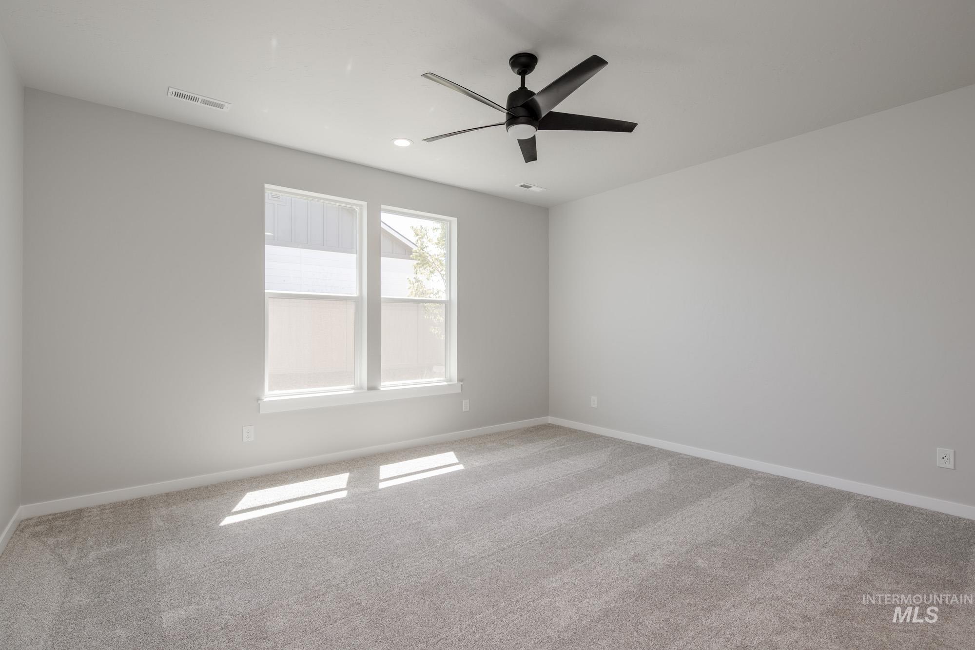 Carpeted empty room featuring ceiling fan and recessed lighting