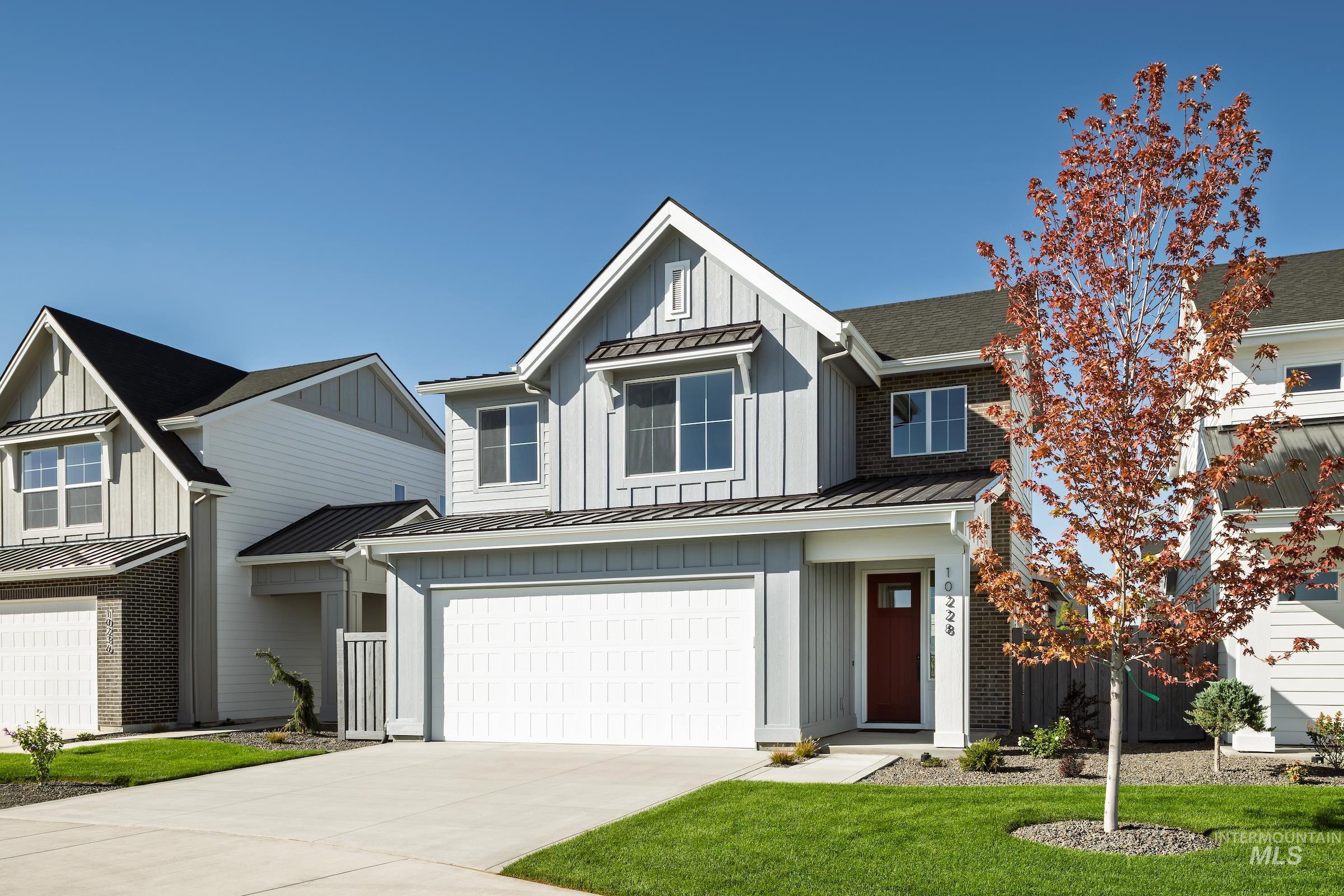 Modern farmhouse featuring a standing seam roof, a metal roof, board and batten siding, a garage, and driveway