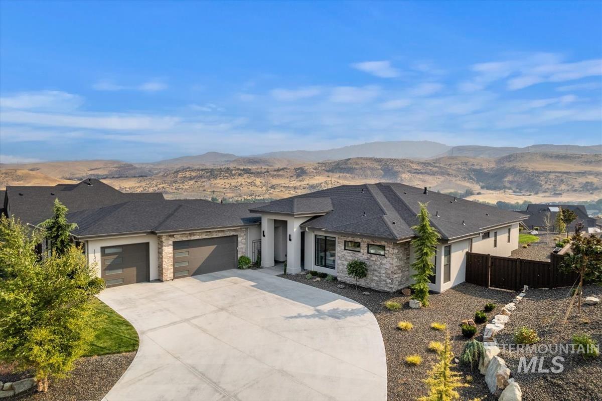 Prairie-style home featuring a garage, driveway, stucco siding, and a mountain view