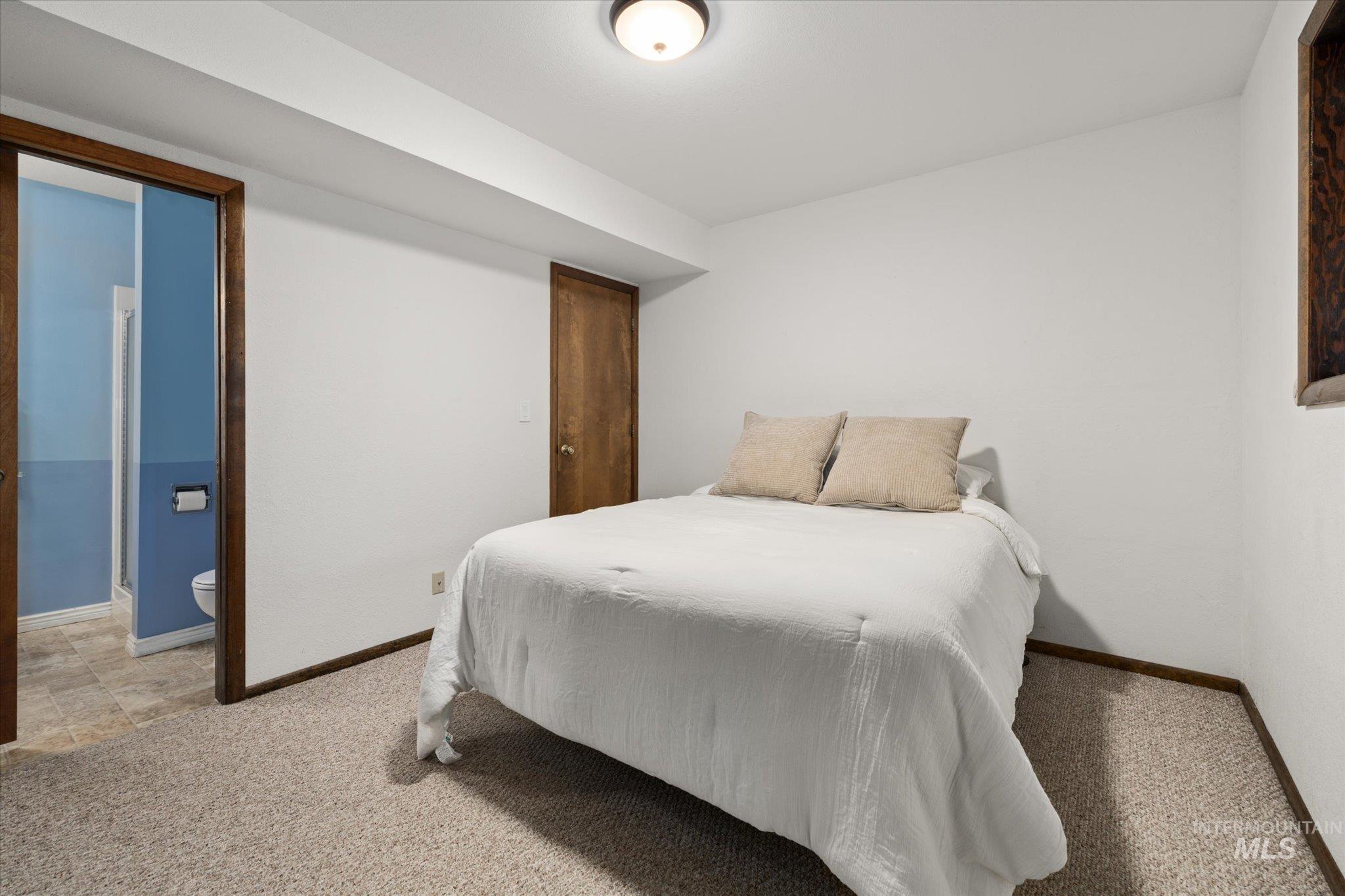 Bedroom with light carpet and connected bathroom