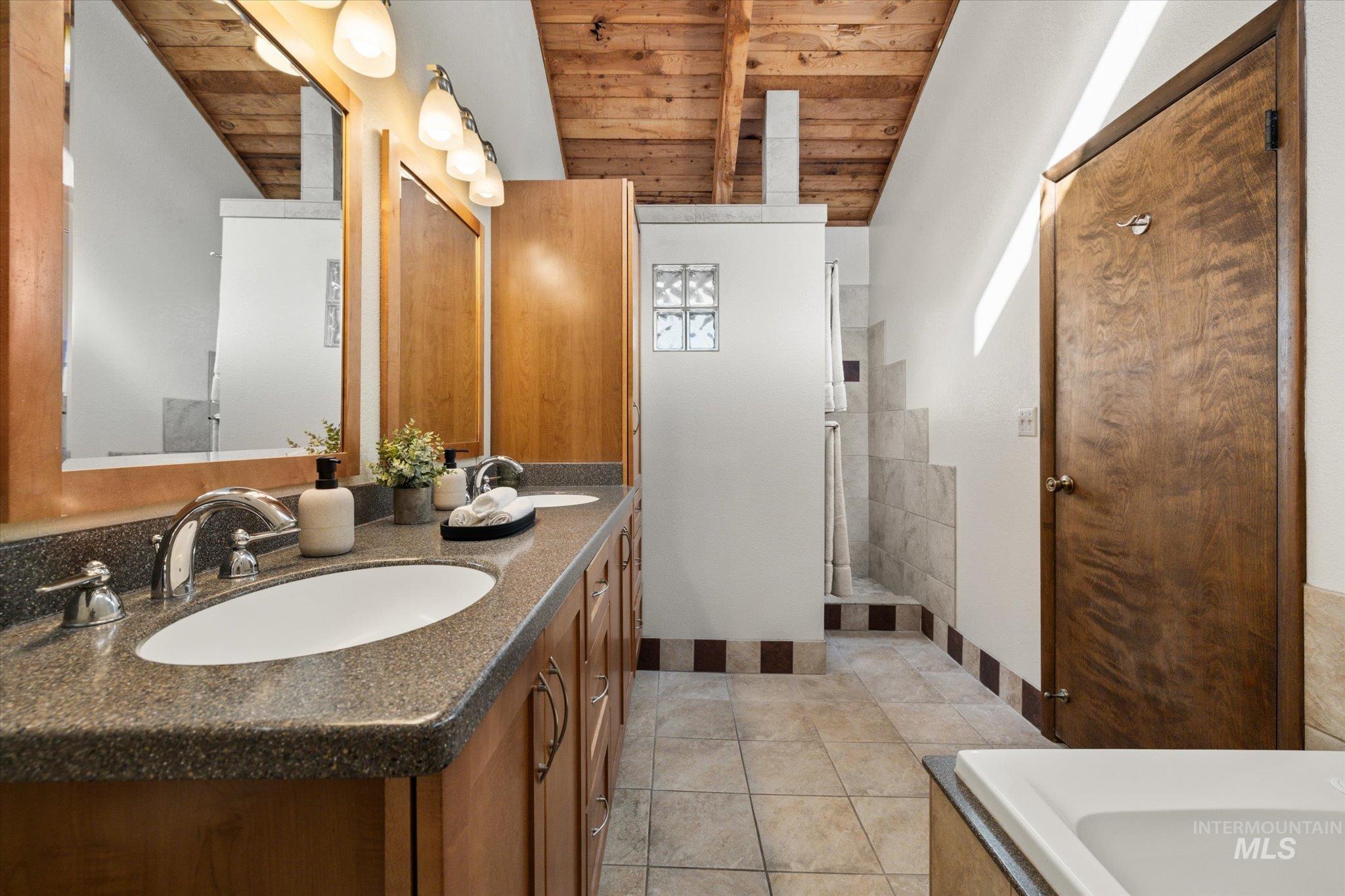 Full bath featuring double vanity, wooden ceiling, and light tile patterned floors