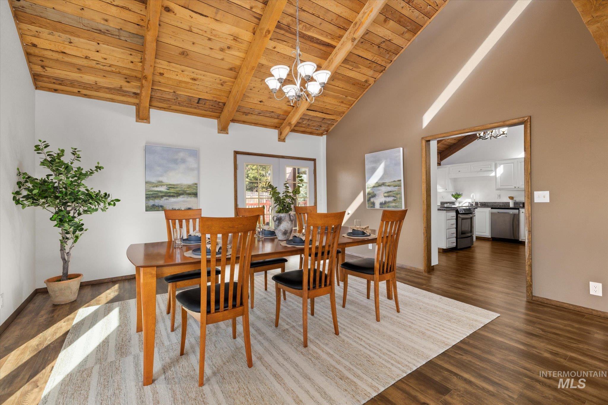 Dining space featuring a chandelier, a wooden ceiling with exposed beams, dark wood-style flooring, and high vaulted ceiling