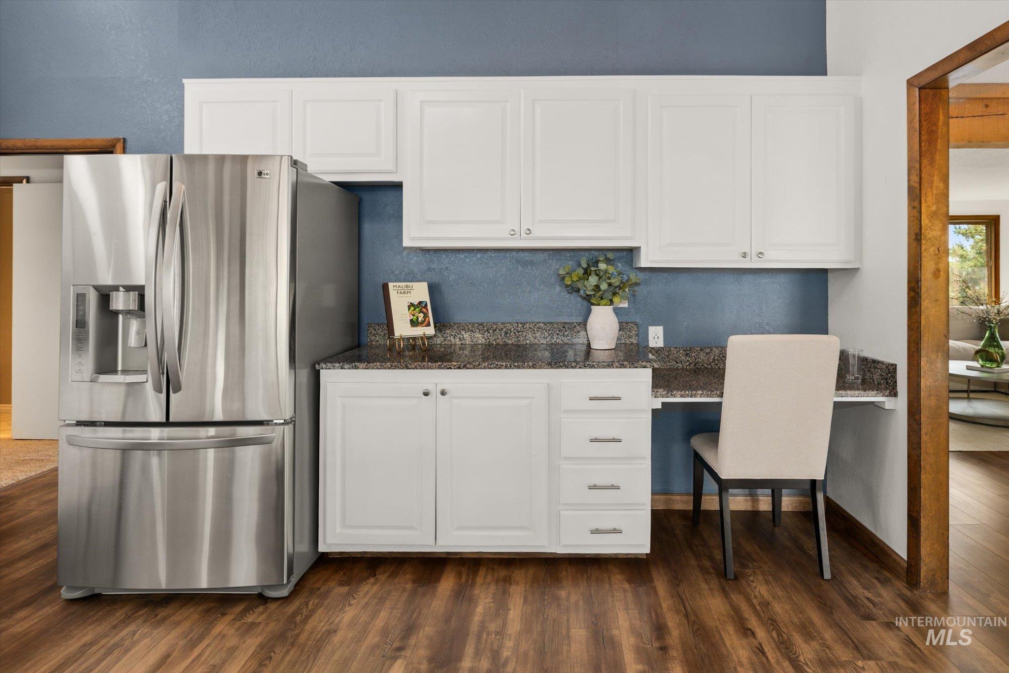 Kitchen featuring stainless steel refrigerator with ice dispenser, white cabinets, and dark wood-style floors
