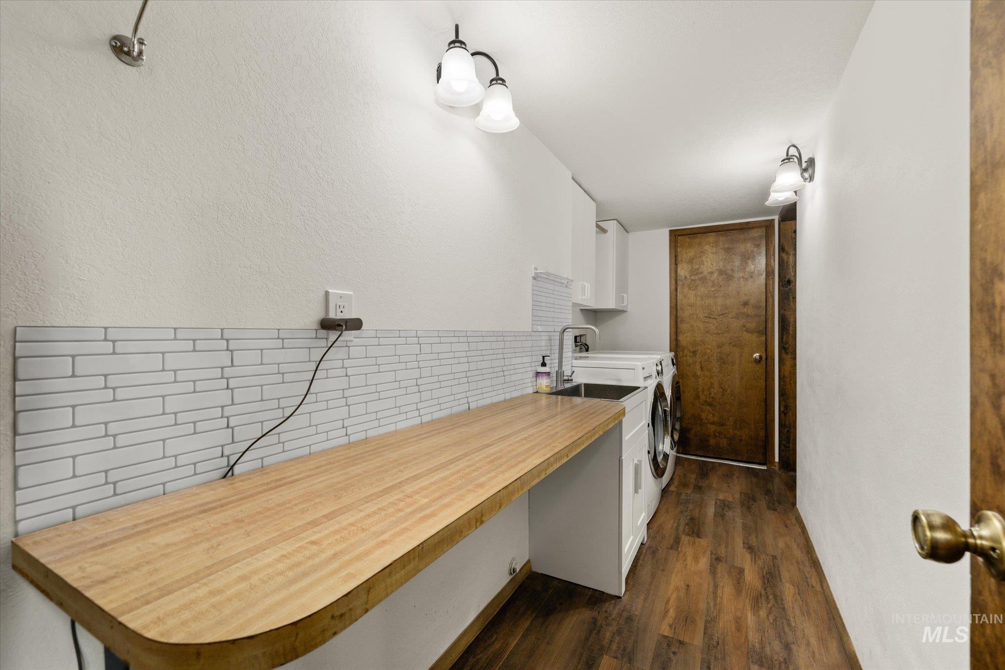 Kitchen featuring white cabinets, dark wood-type flooring, light countertops, tasteful backsplash, and a textured wall