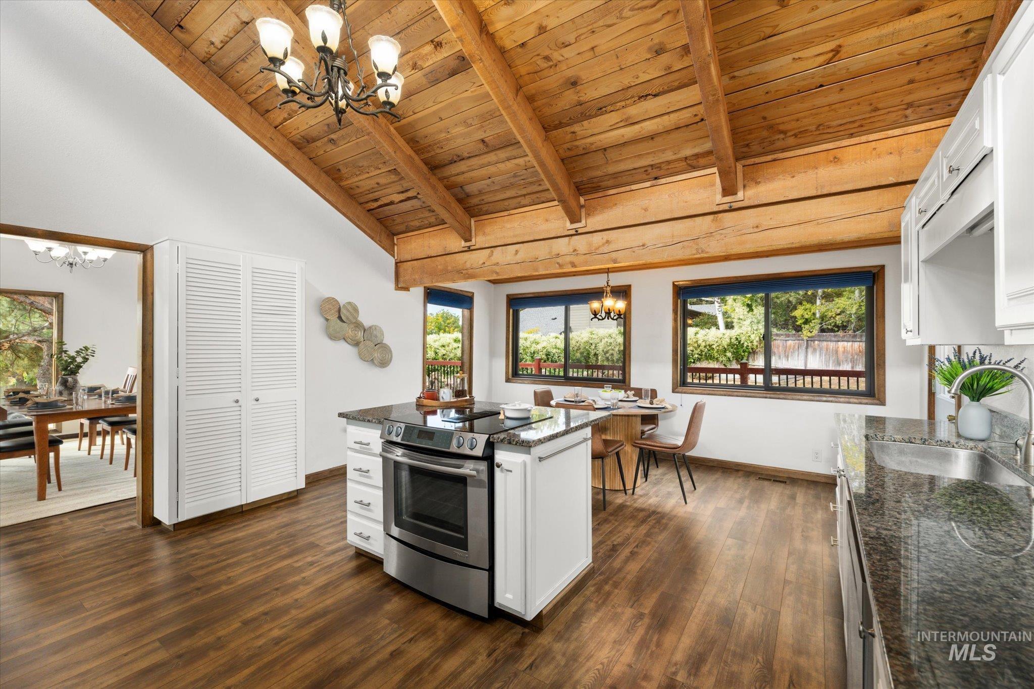 Kitchen with a chandelier, hanging light fixtures, white cabinetry, a wooden ceiling with exposed beams, and stainless steel range with electric stovetop