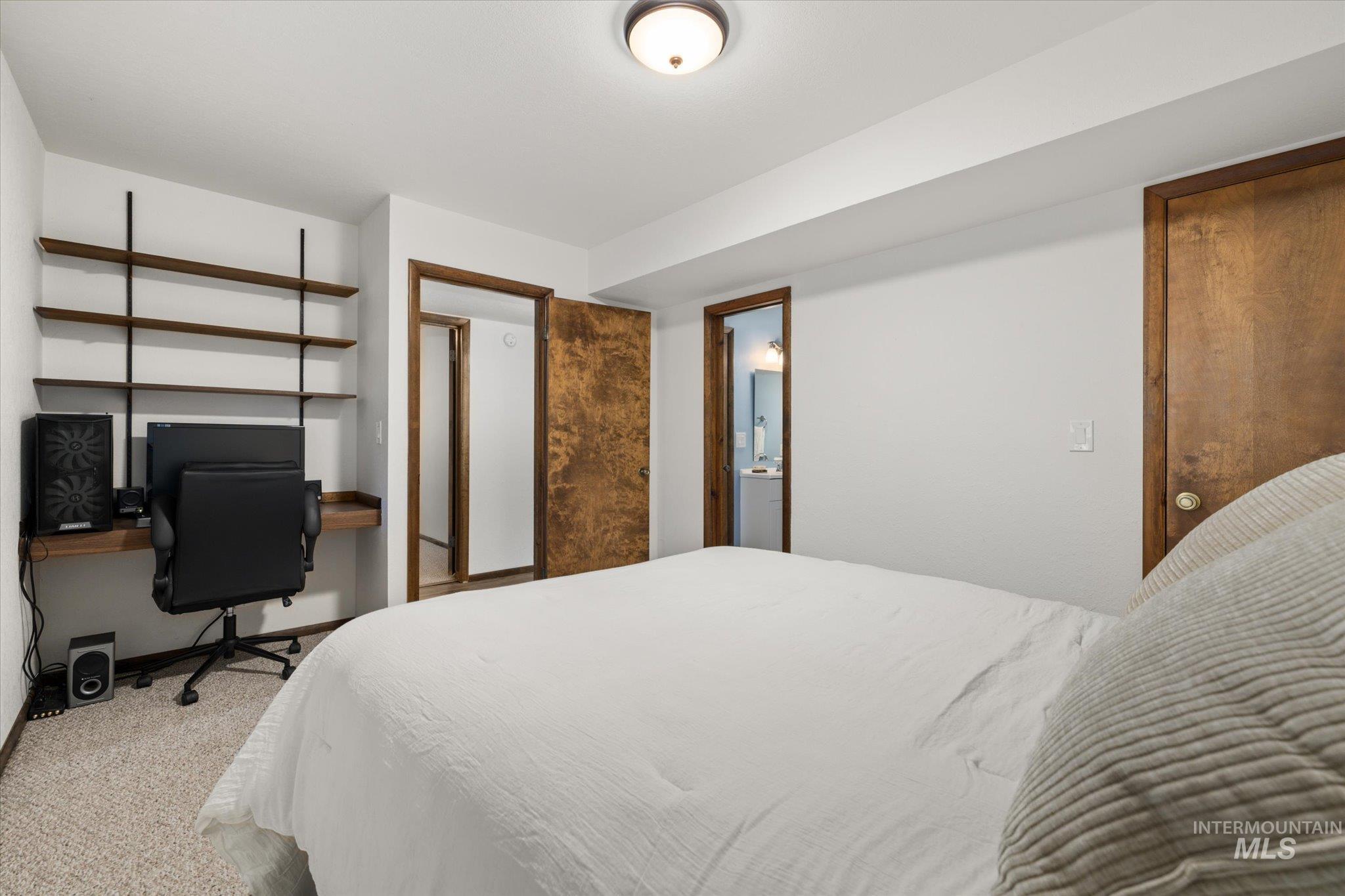 Carpeted bedroom featuring a desk and ensuite bath