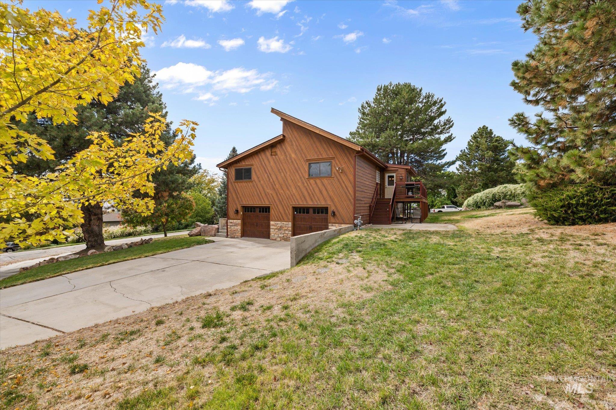 View of home's exterior featuring stairway, a garage, concrete driveway, stone siding, and a lawn