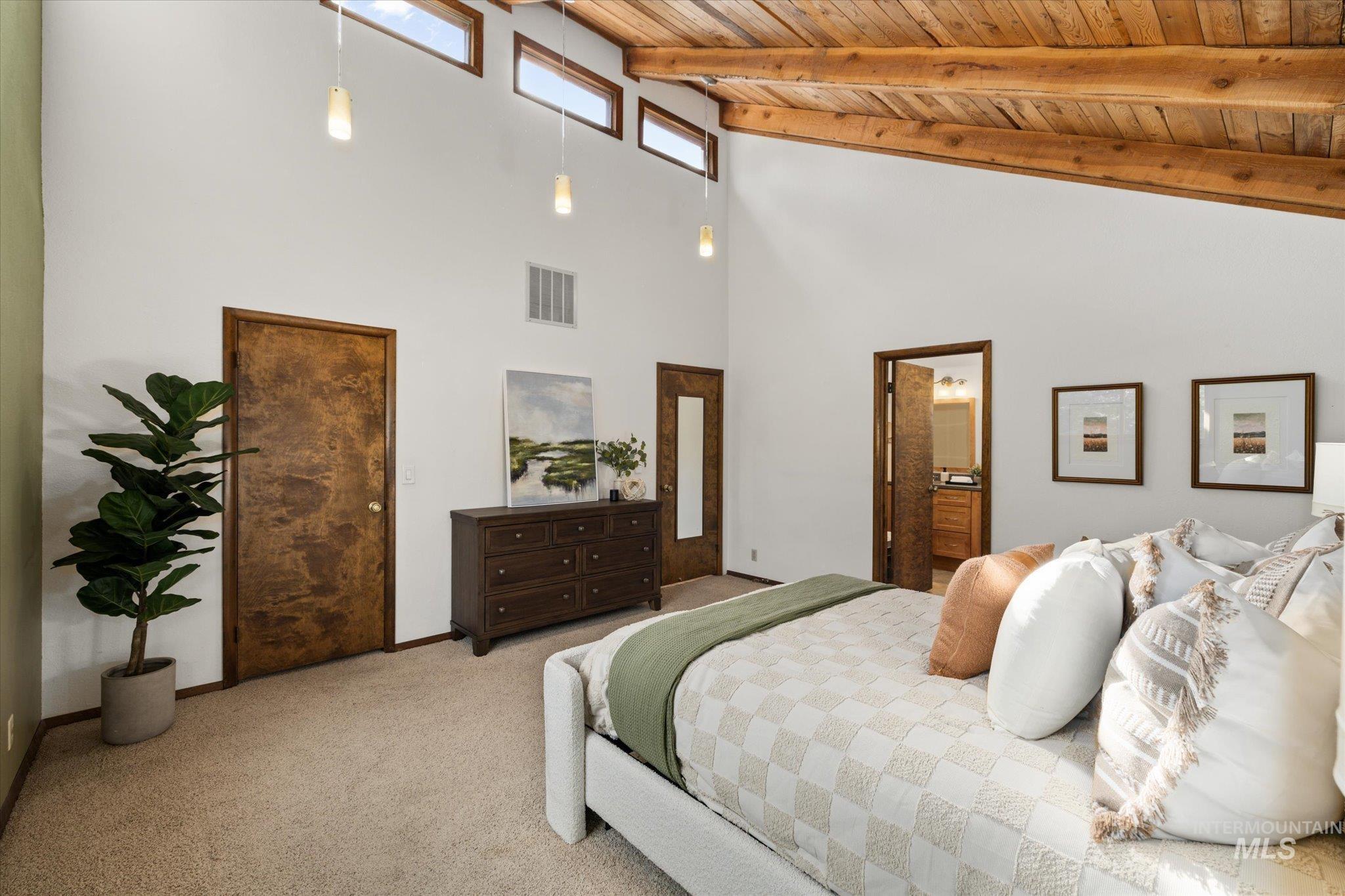 Carpeted bedroom with high vaulted ceiling and a wood ceiling with exposed beams