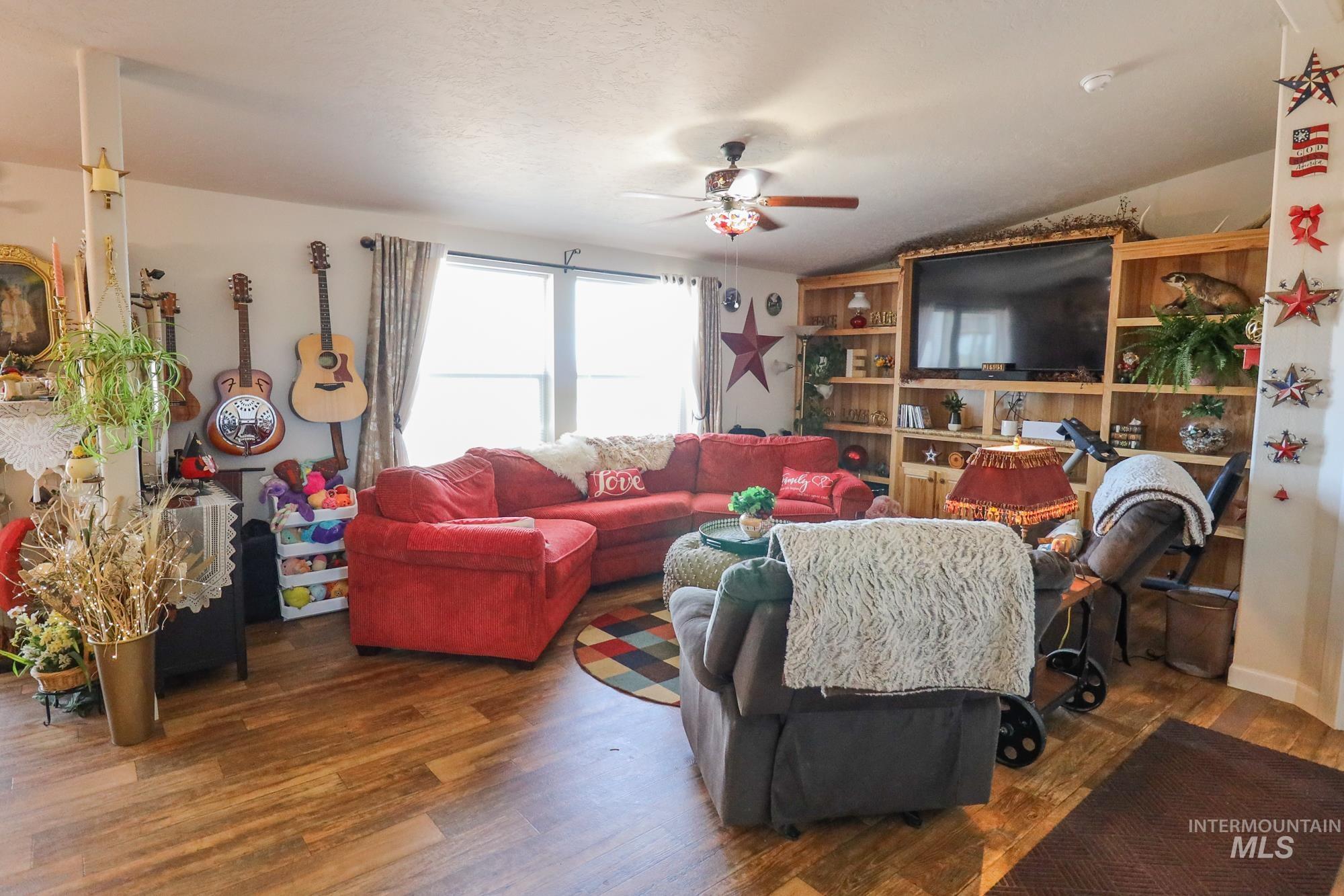 Living area featuring a ceiling fan, wood finished floors, and lofted ceiling