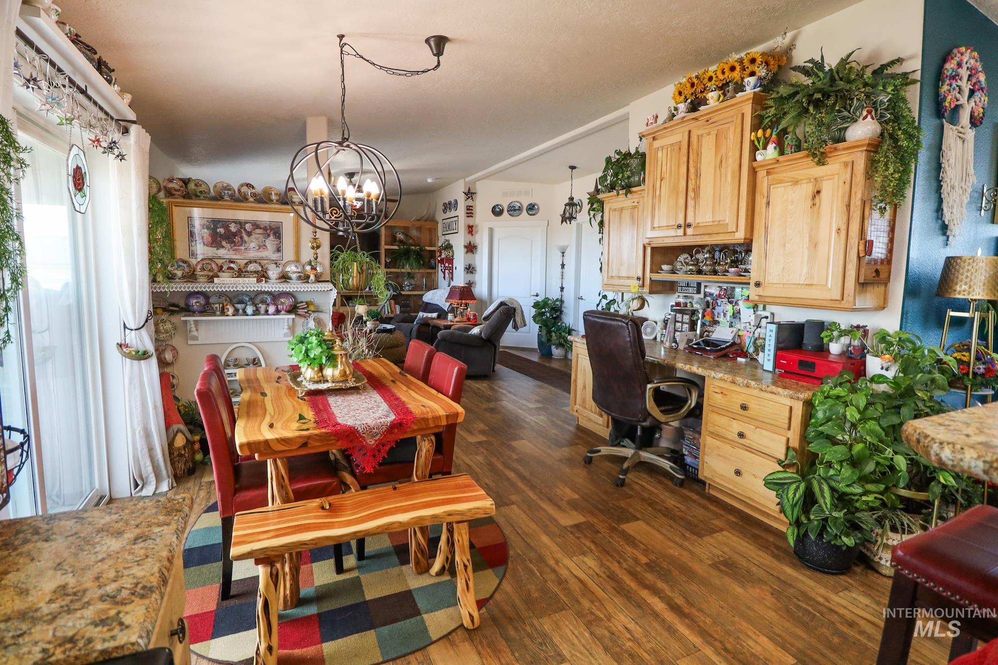 Dining area with dark wood-style floors, a chandelier, and a desk
