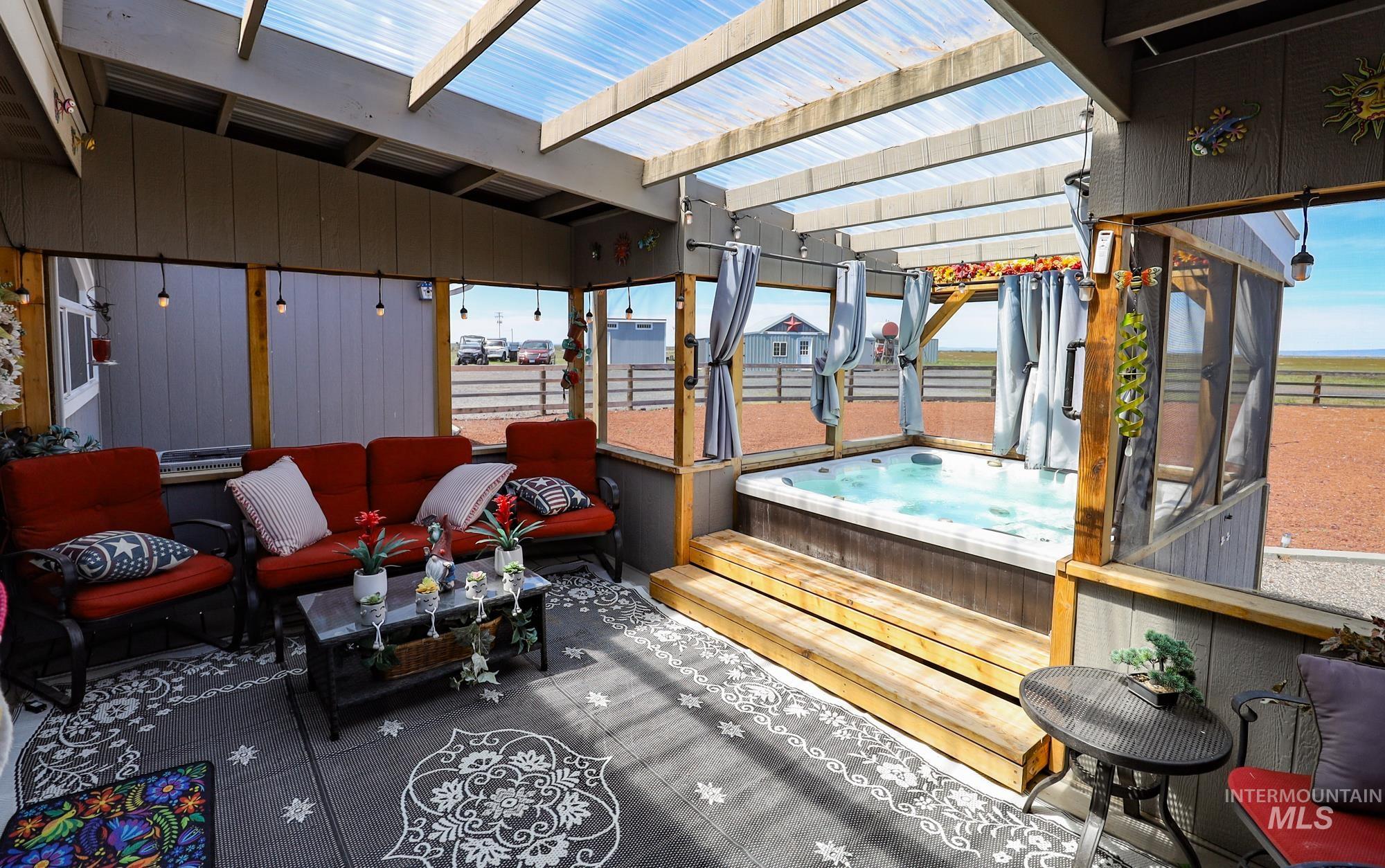 Deck featuring a covered hot tub, an outdoor hangout area, and a pergola