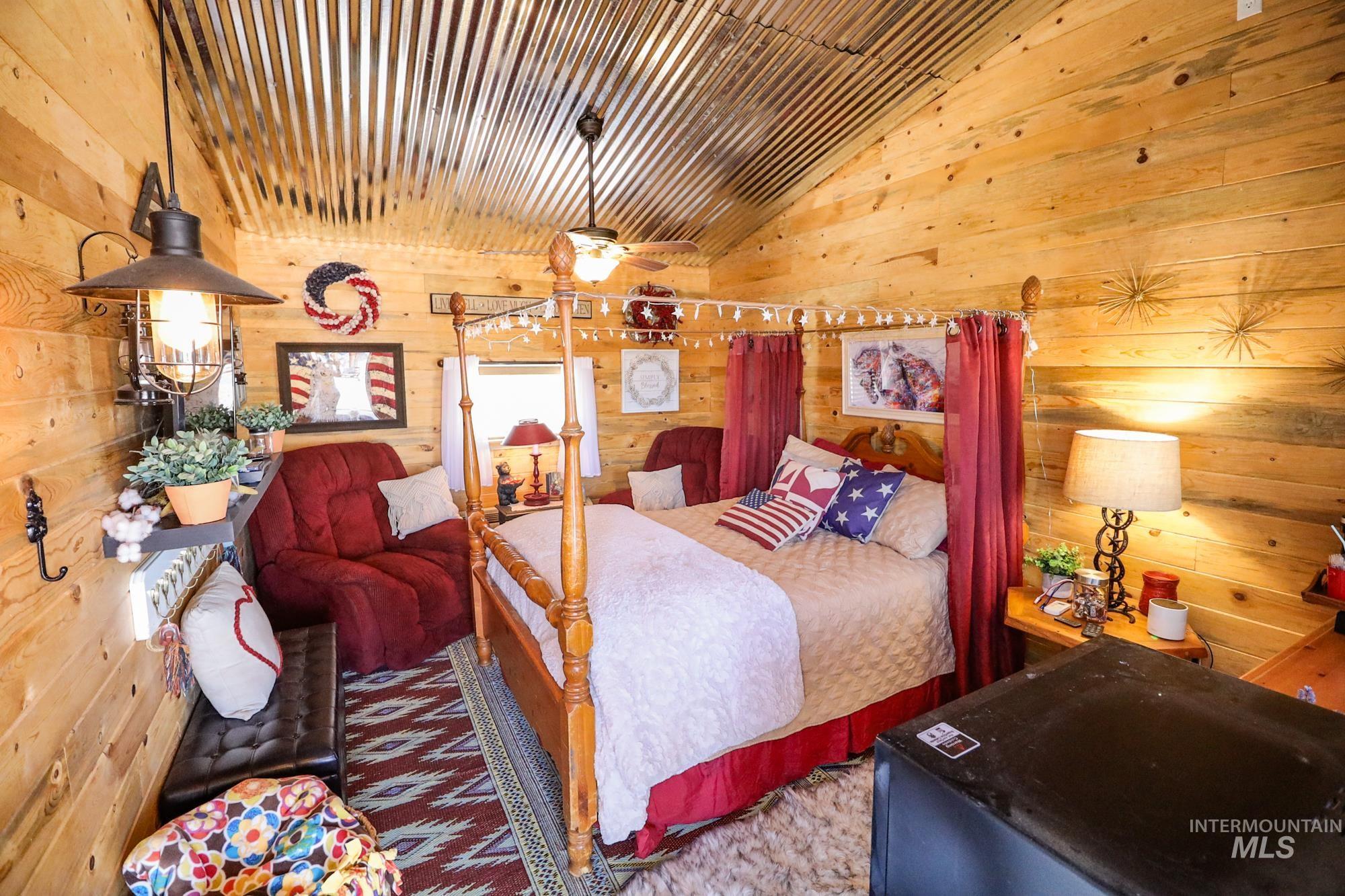 Carpeted bedroom featuring wooden walls and lofted ceiling