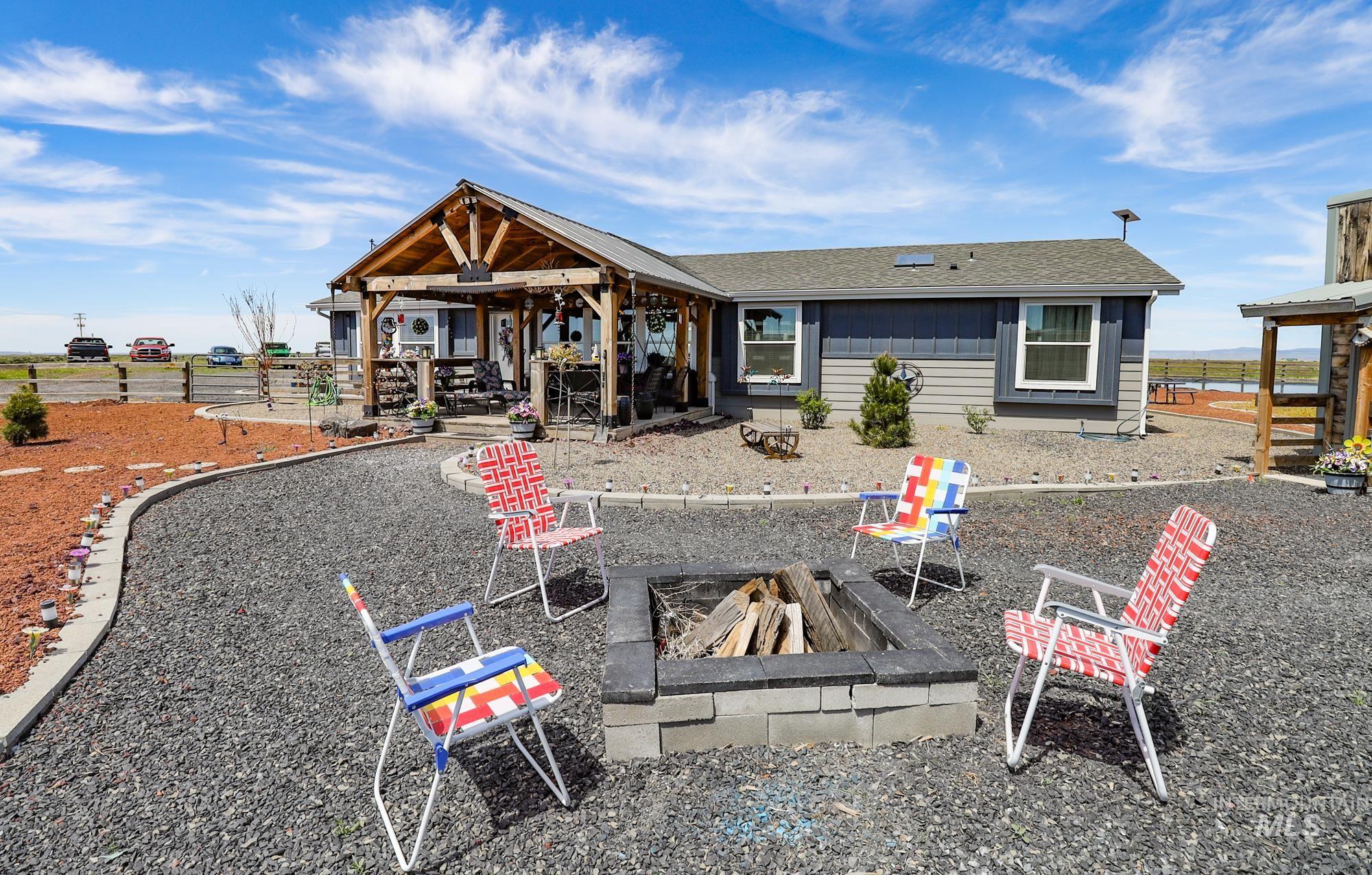 Rear view of property with a fire pit, roof with shingles, a gazebo, and a patio area