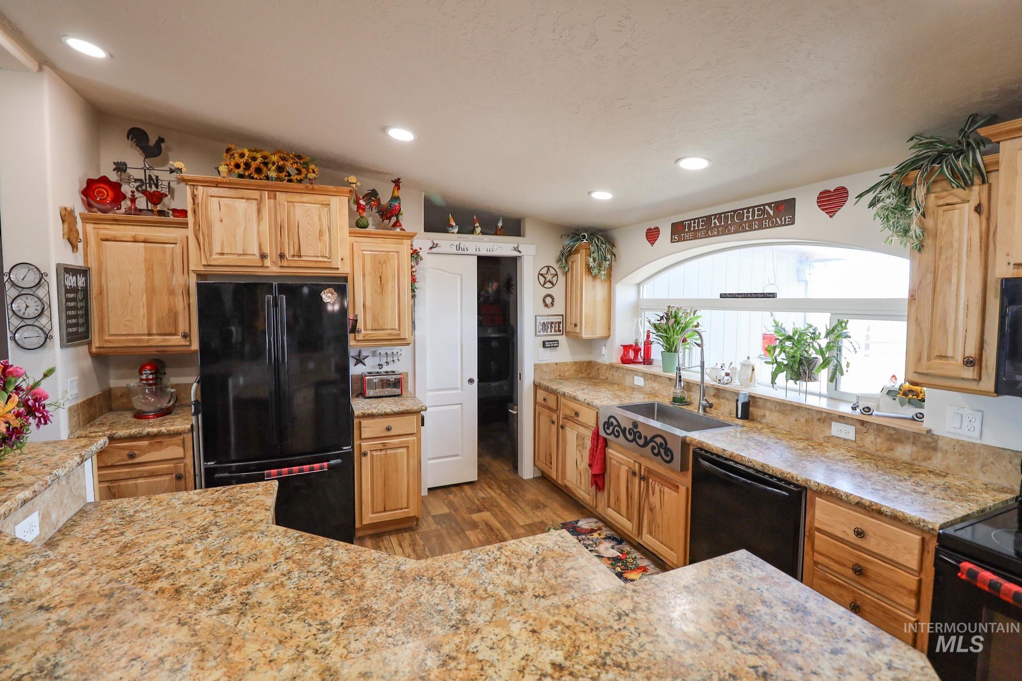 Kitchen featuring black appliances, light wood-style floors, recessed lighting, and light stone countertops