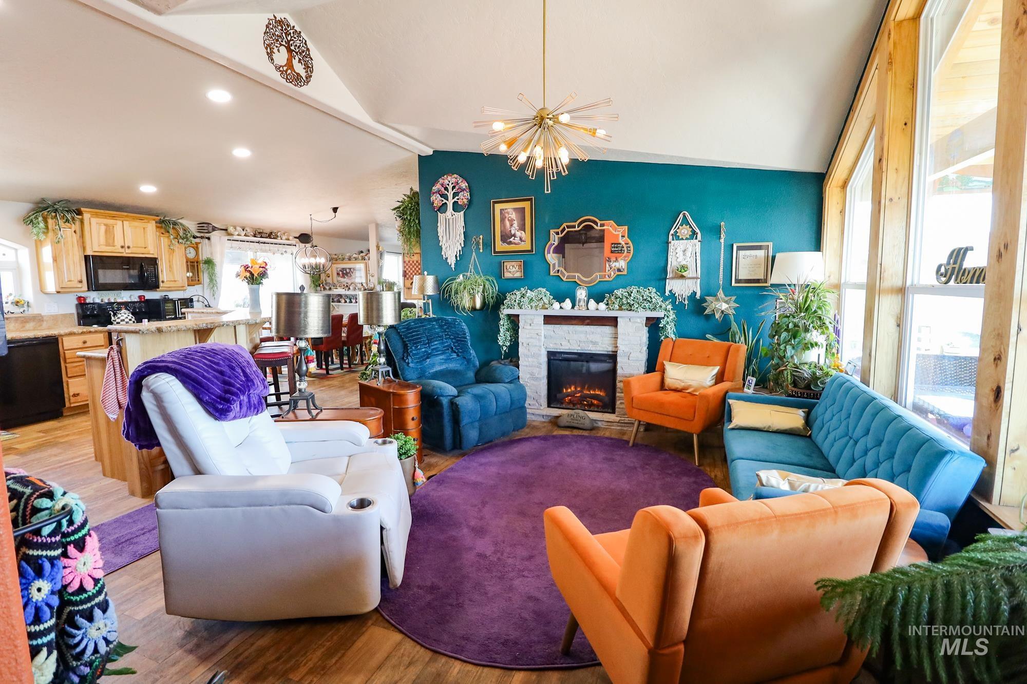 Living room with vaulted ceiling, light wood-style flooring, a fireplace, recessed lighting, and a chandelier