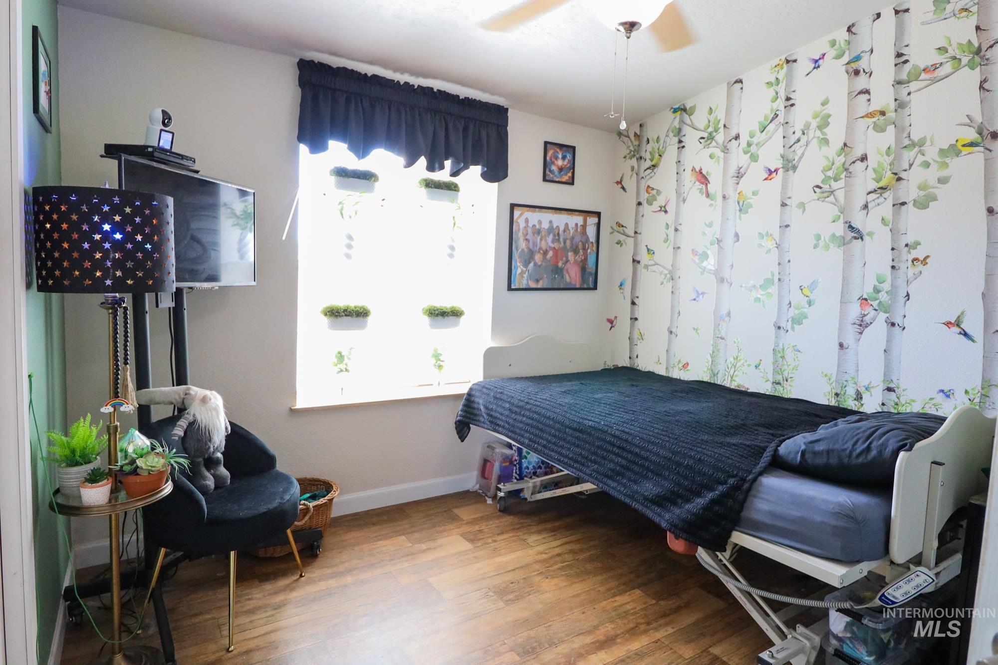 Bedroom featuring wood finished floors, multiple windows, and ceiling fan