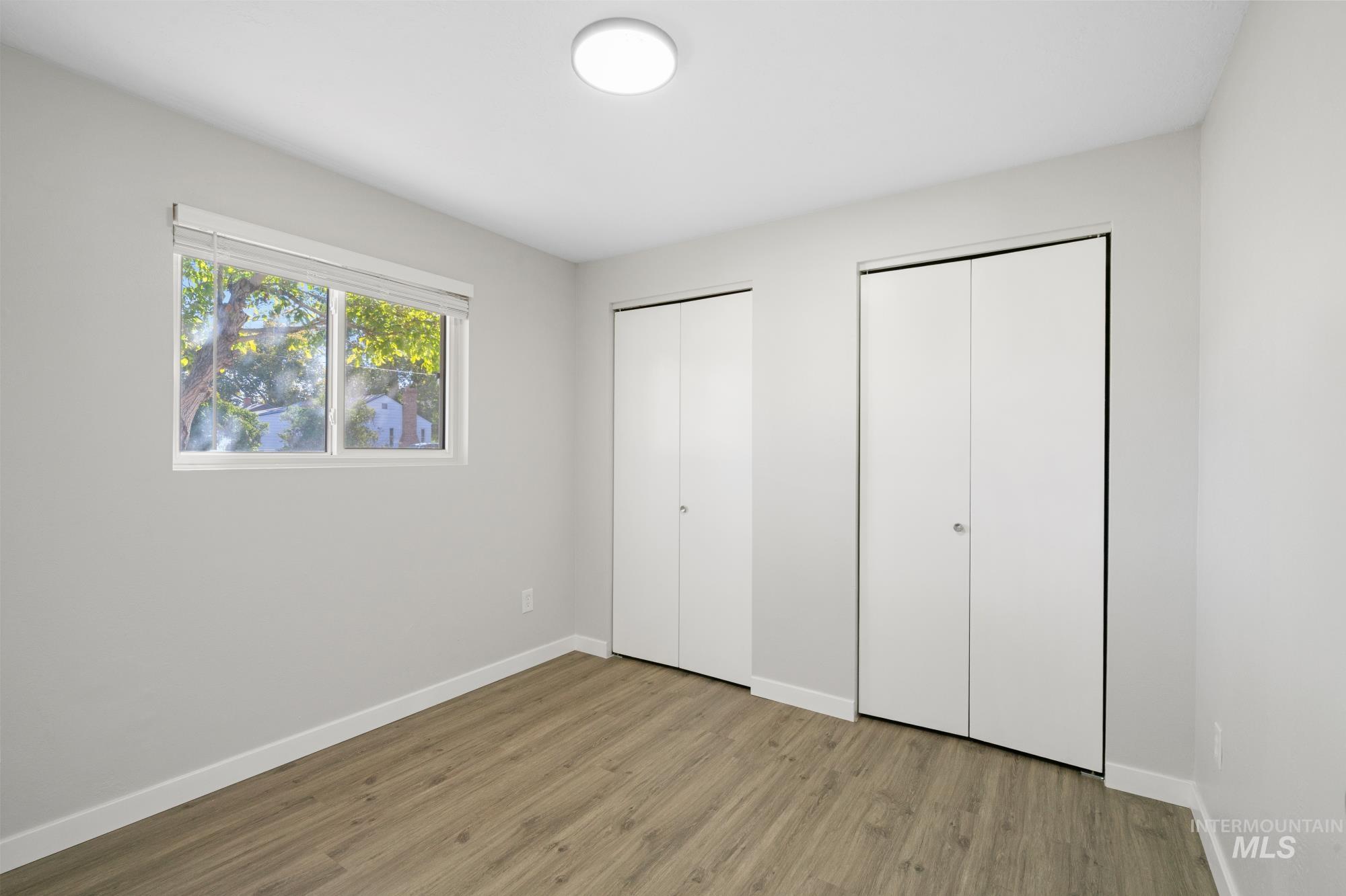 Unfurnished bedroom with two closets and wood finished floors