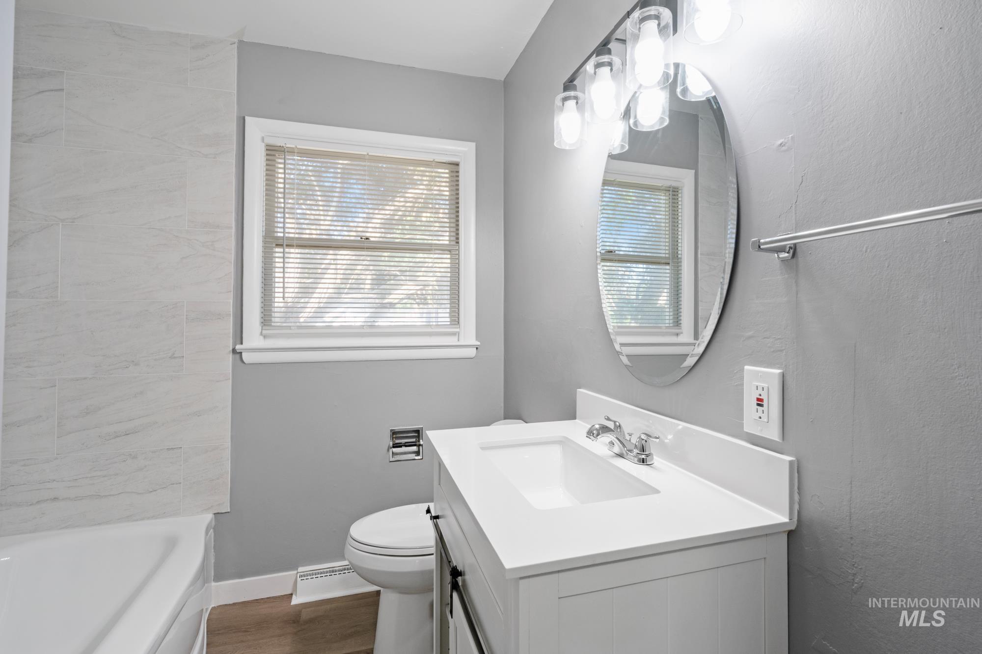 Bathroom with vanity, a baseboard heating unit, and dark wood-type flooring
