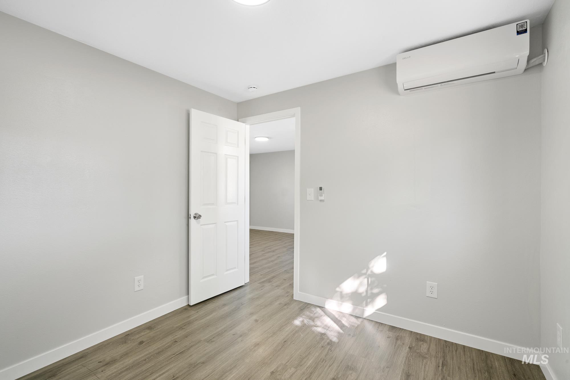 Unfurnished room featuring an AC wall unit and light wood-style flooring