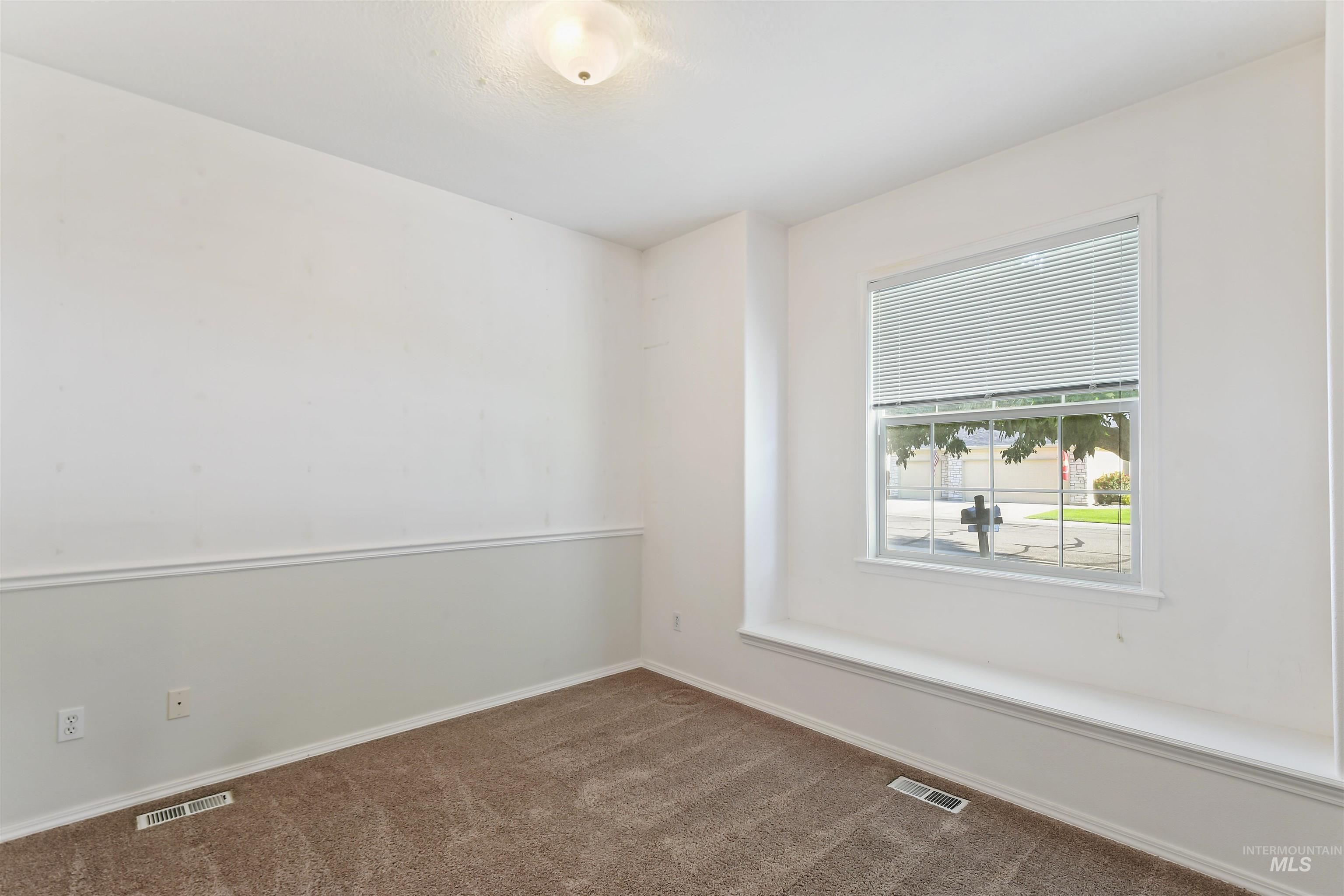 Empty room with dark colored carpet and baseboards