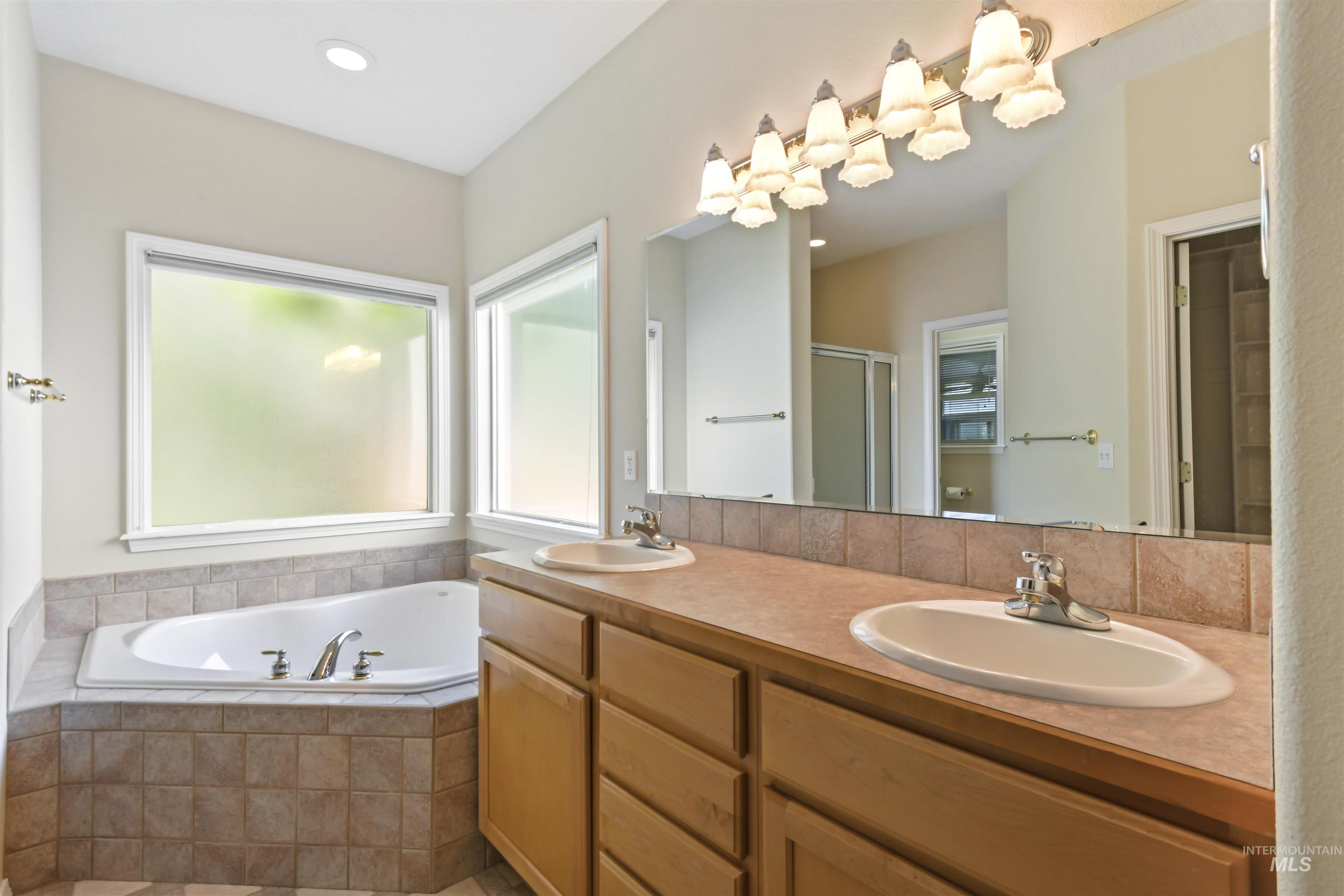 Bathroom with a stall shower, a garden tub, double vanity, and recessed lighting
