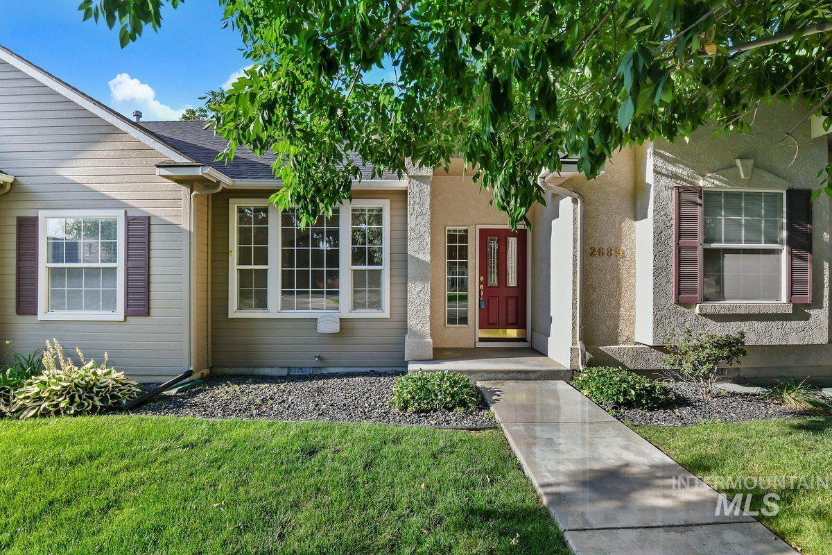 Entrance to property with a lawn and a shingled roof