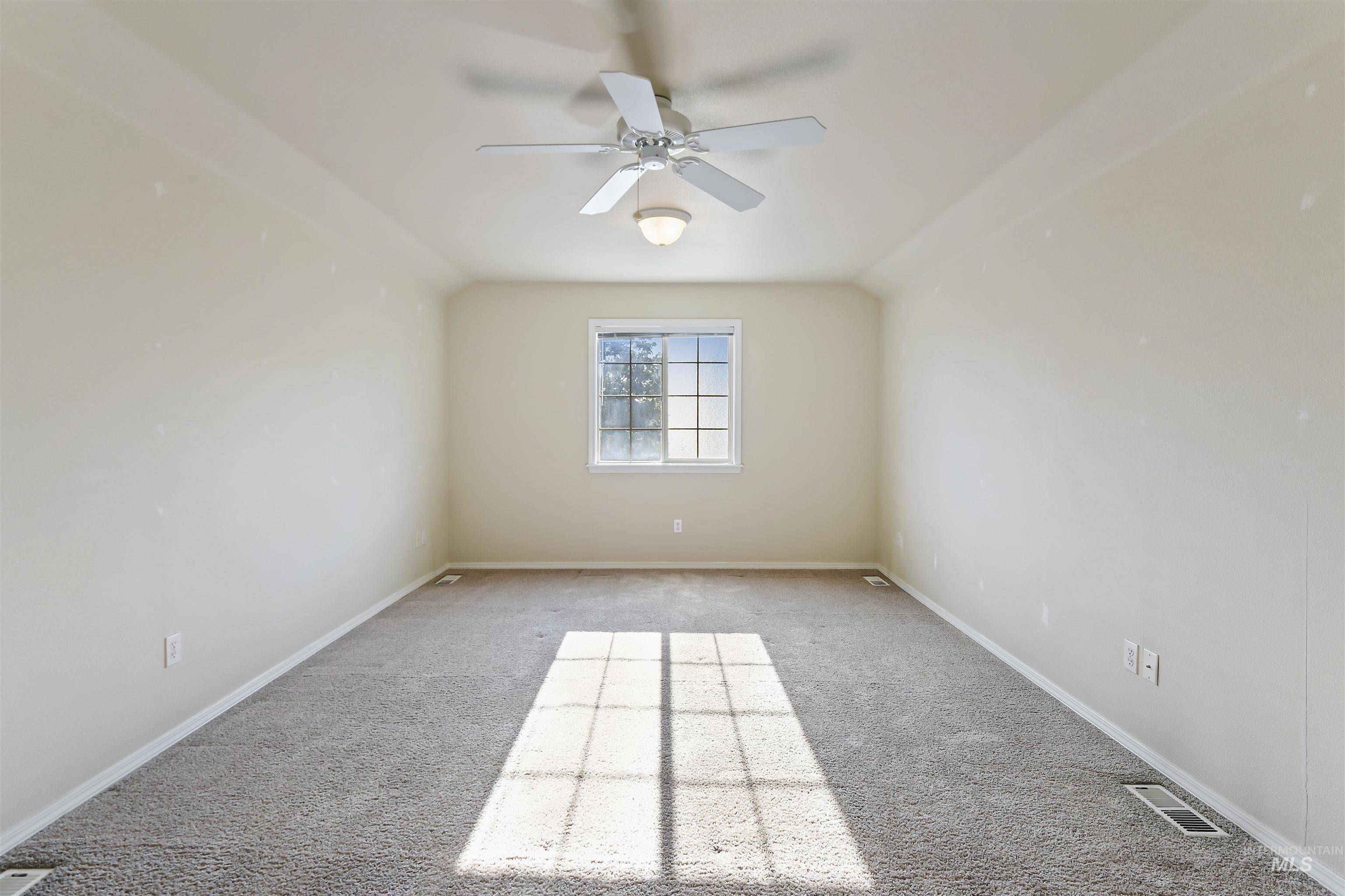Carpeted empty room featuring a ceiling fan and baseboards