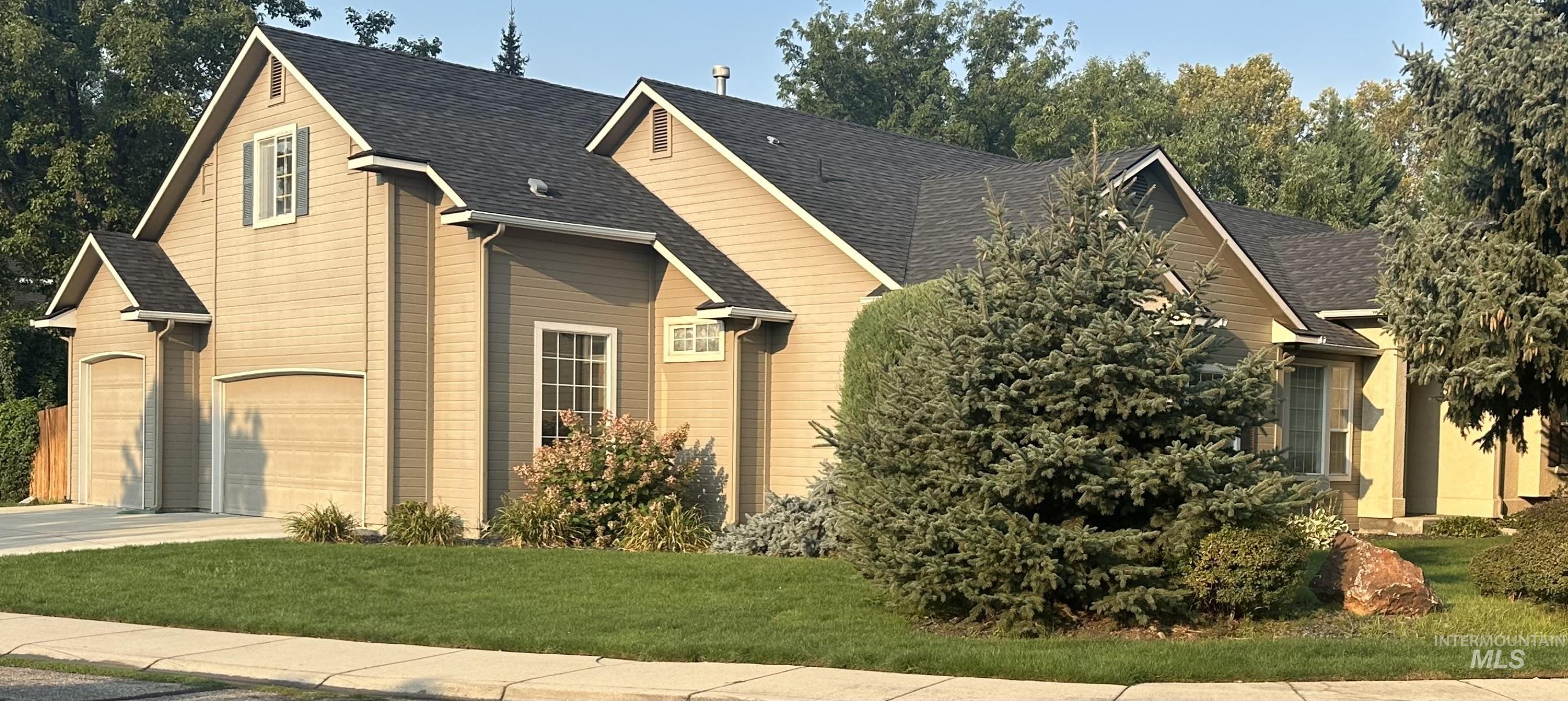 View of front of house featuring roof with shingles, a front yard, and concrete driveway
