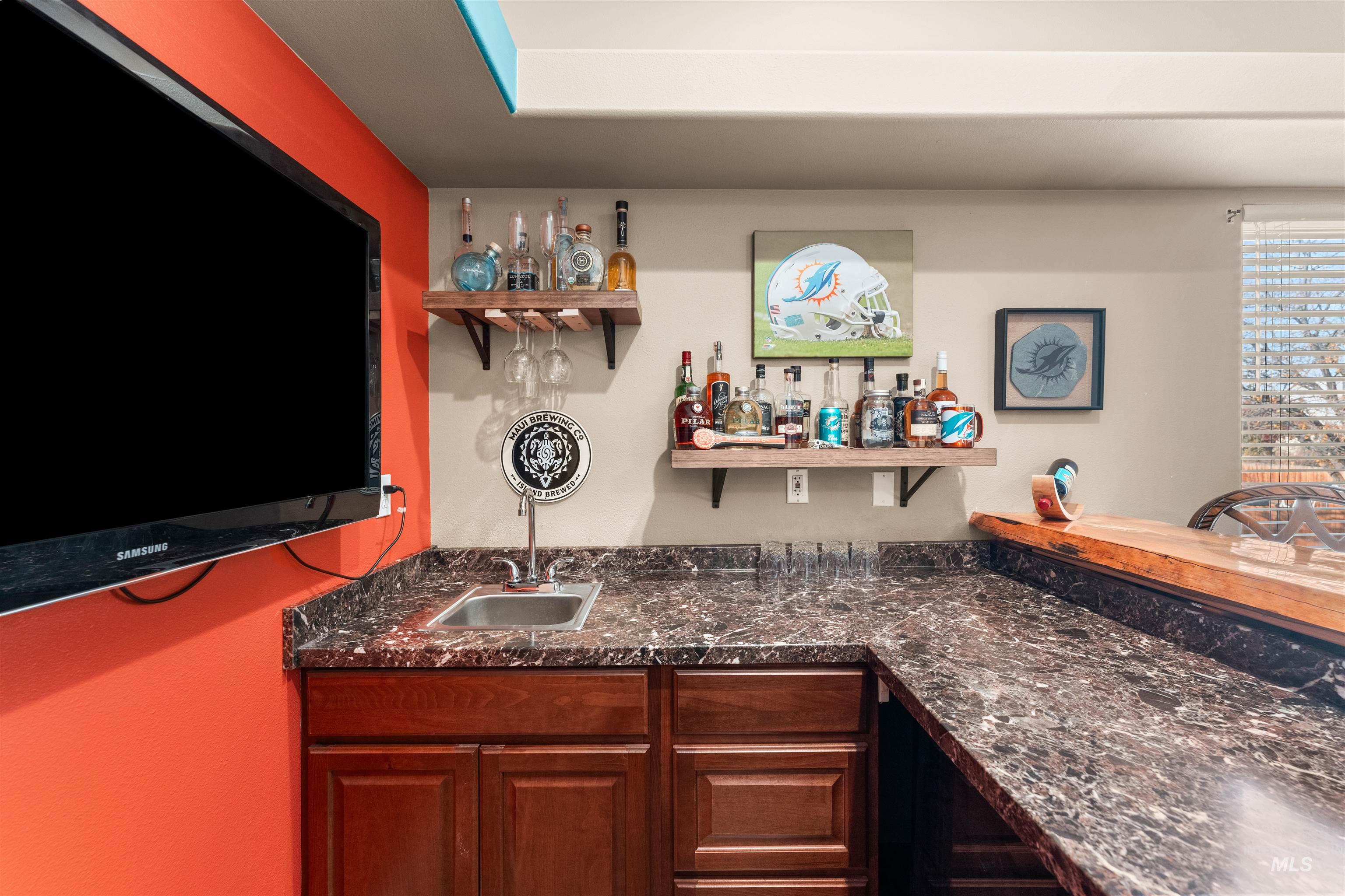 Indoor wet bar with open shelves and dark stone countertops