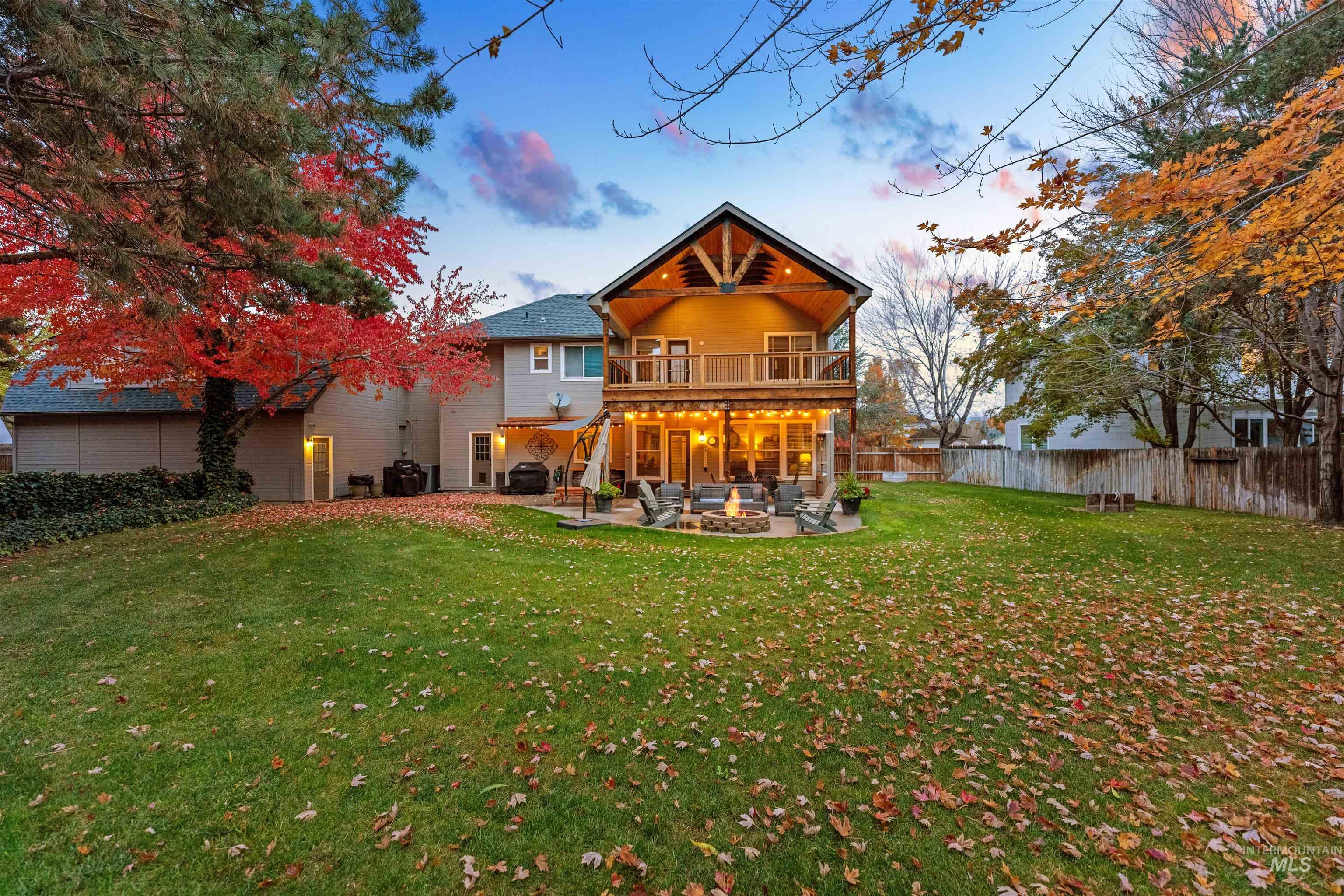 Back of property at dusk featuring a patio, an outdoor fire pit, a fenced backyard, and a balcony