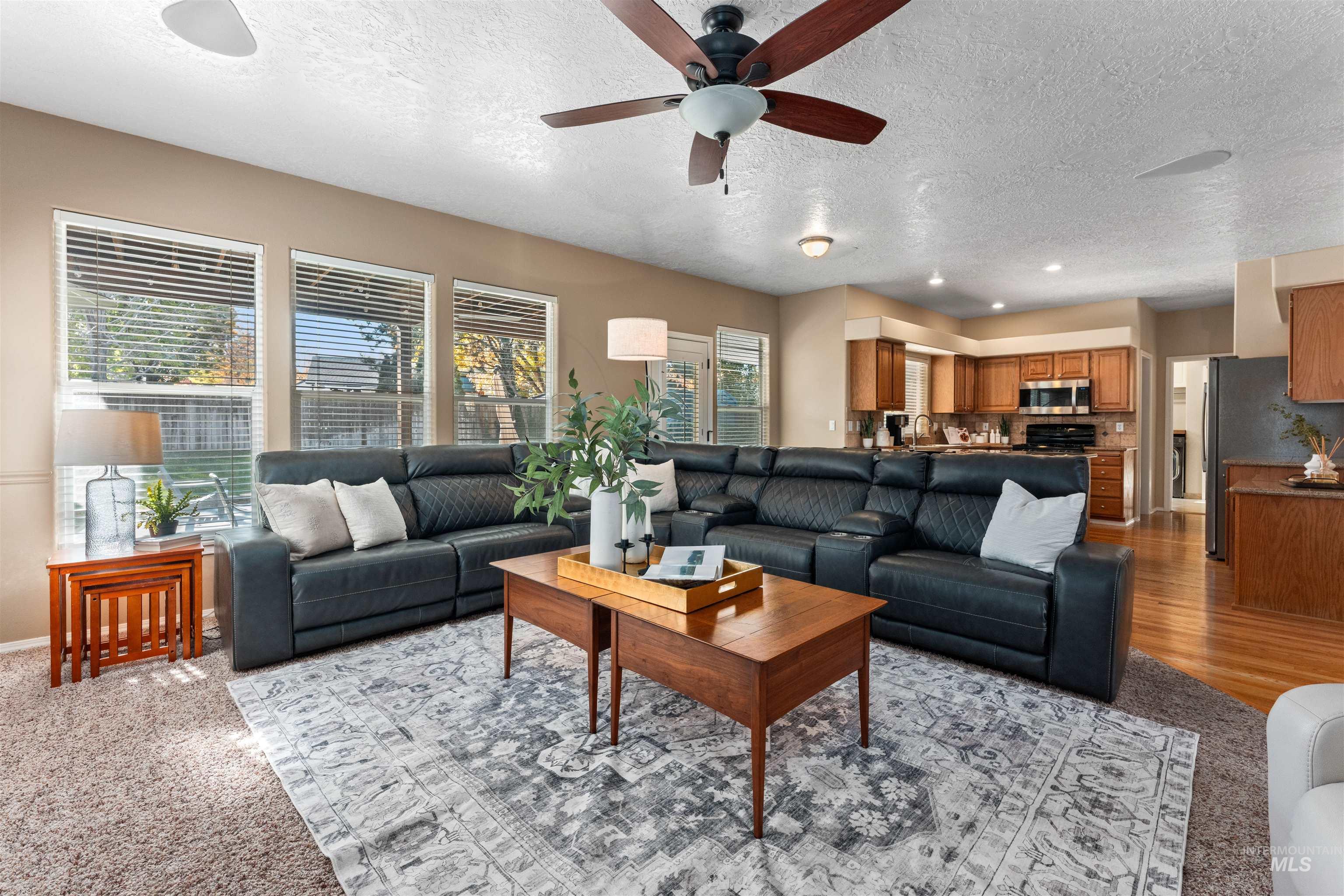 Living area featuring a textured ceiling, a ceiling fan, light colored carpet, and recessed lighting