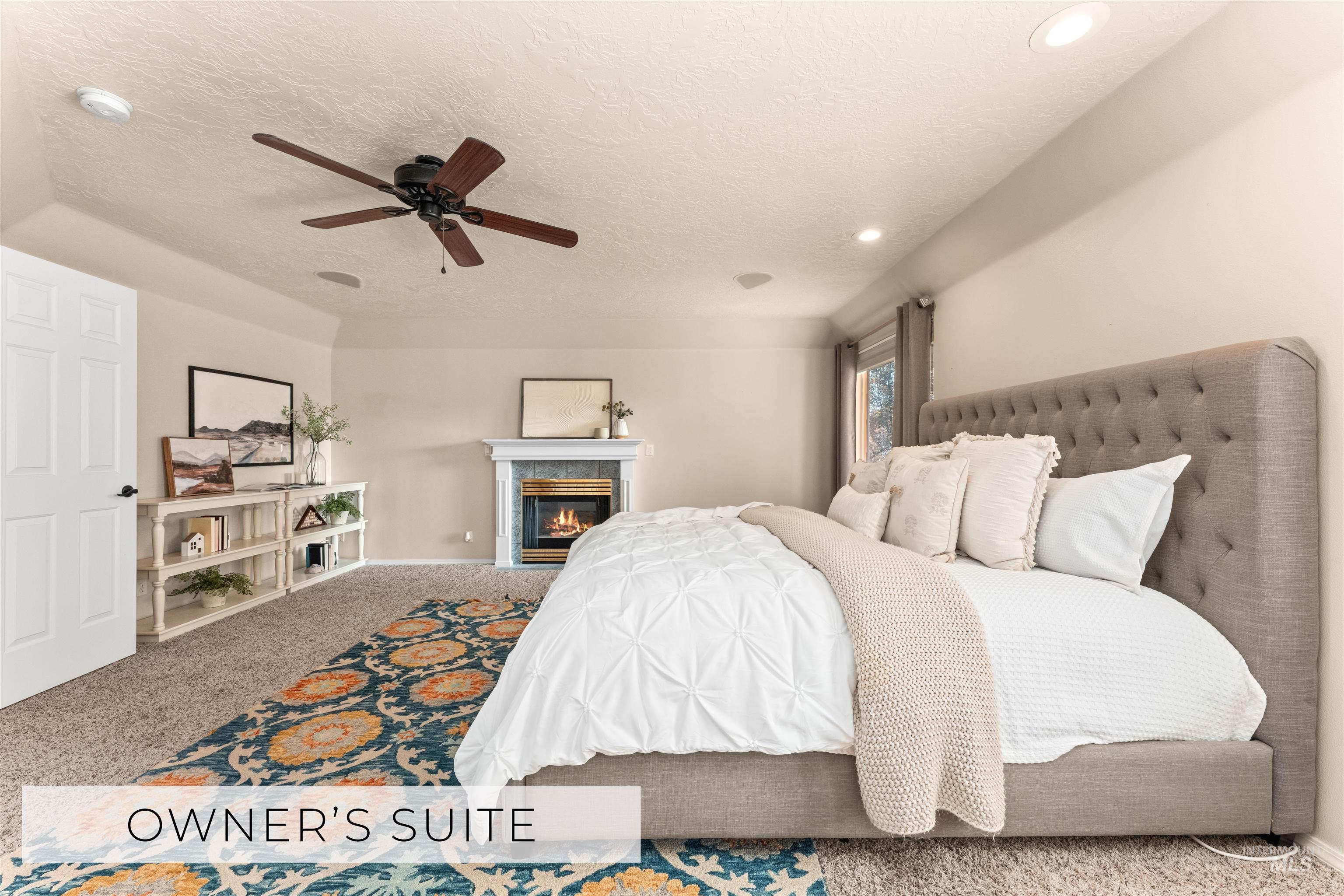 Bedroom with carpet, a tiled fireplace, a textured ceiling, and ceiling fan