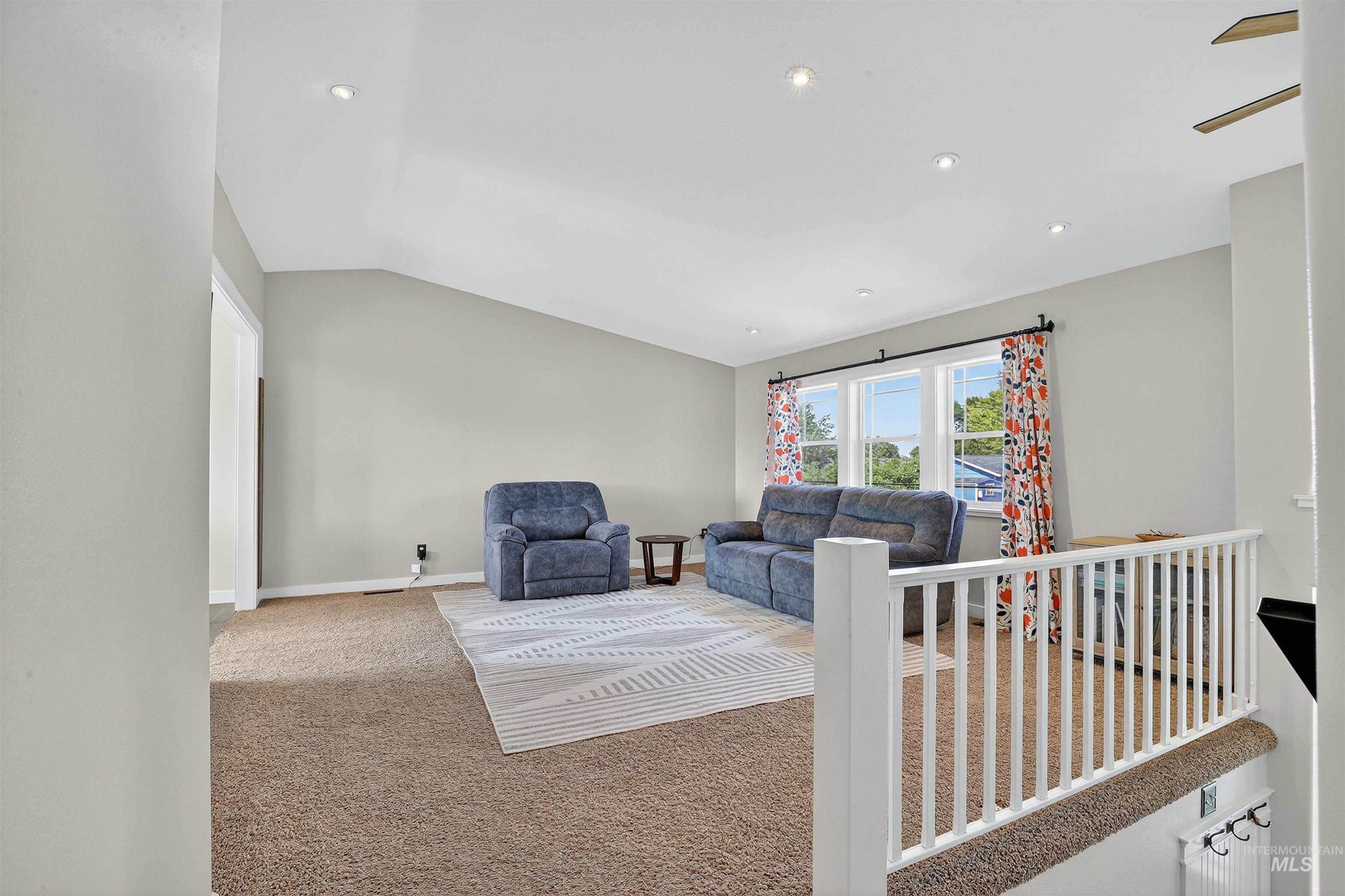 Carpeted living area with vaulted ceiling and recessed lighting