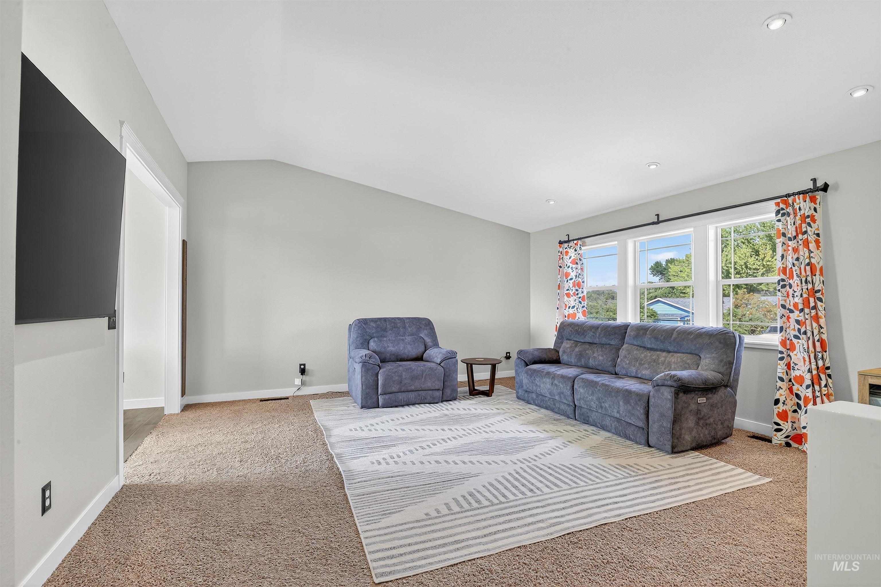 Living area with light carpet and vaulted ceiling