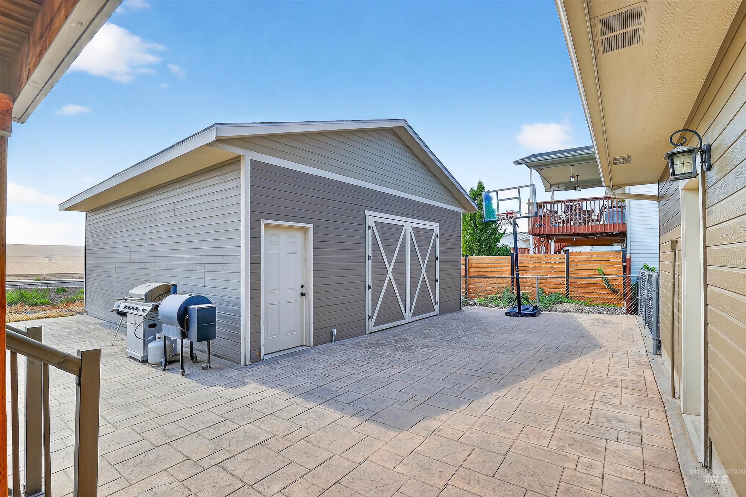 View of patio with an outbuilding and a grill