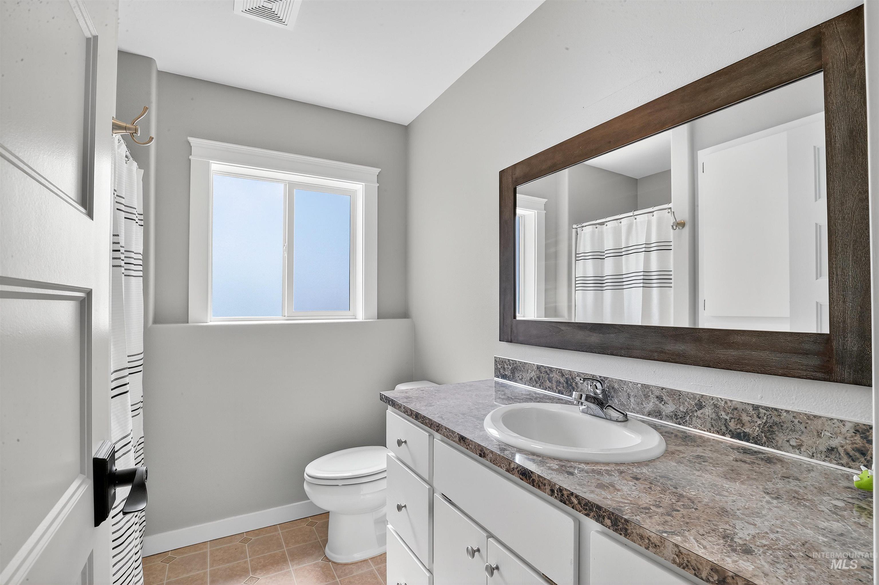 Full bath featuring vanity, light tile patterned floors, and curtained shower