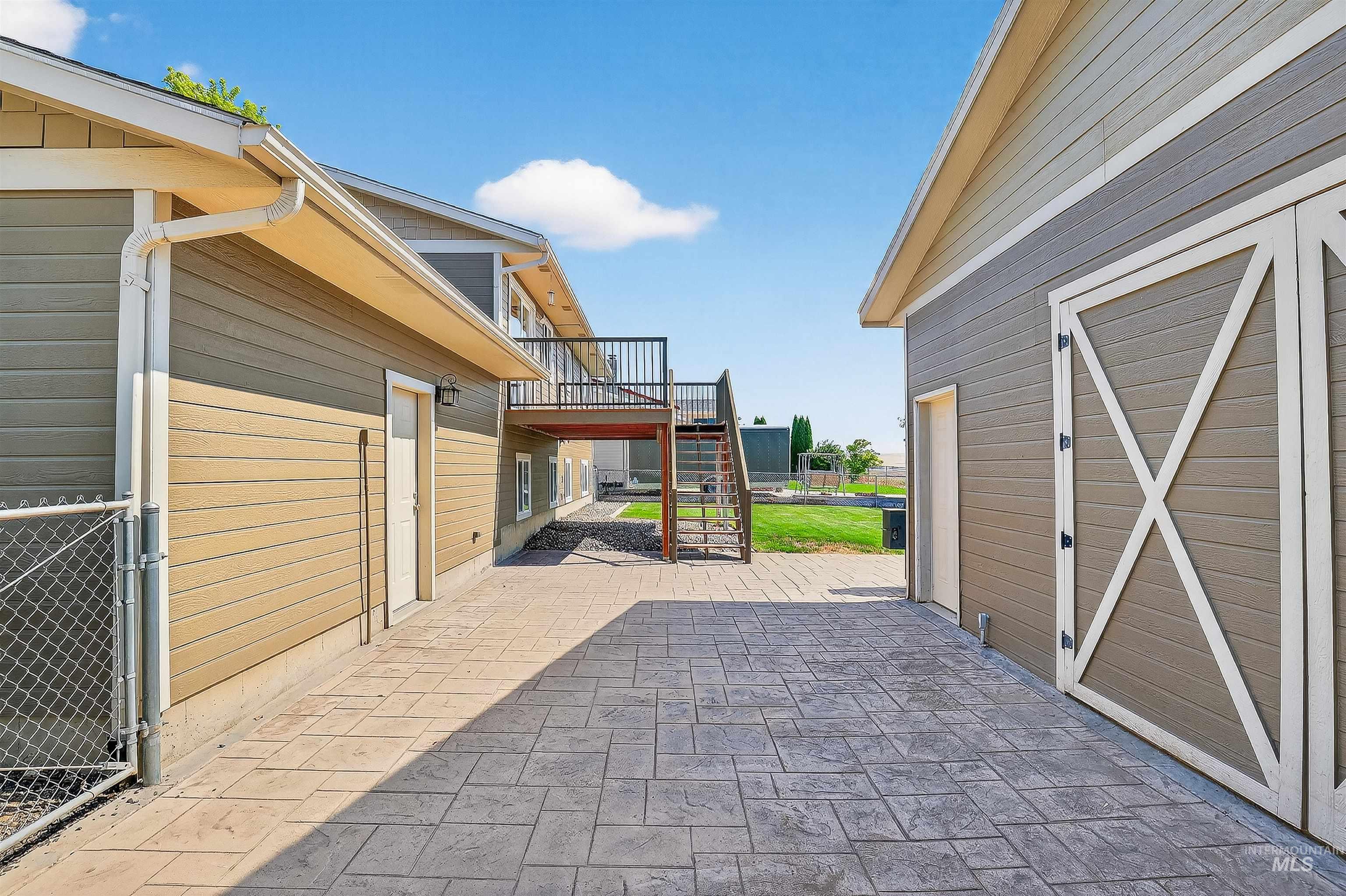 View of patio with stairs, a wooden deck, and an outbuilding