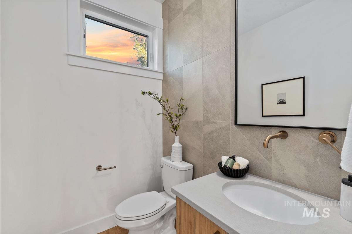 Half bathroom with vanity, tile walls, and tasteful backsplash