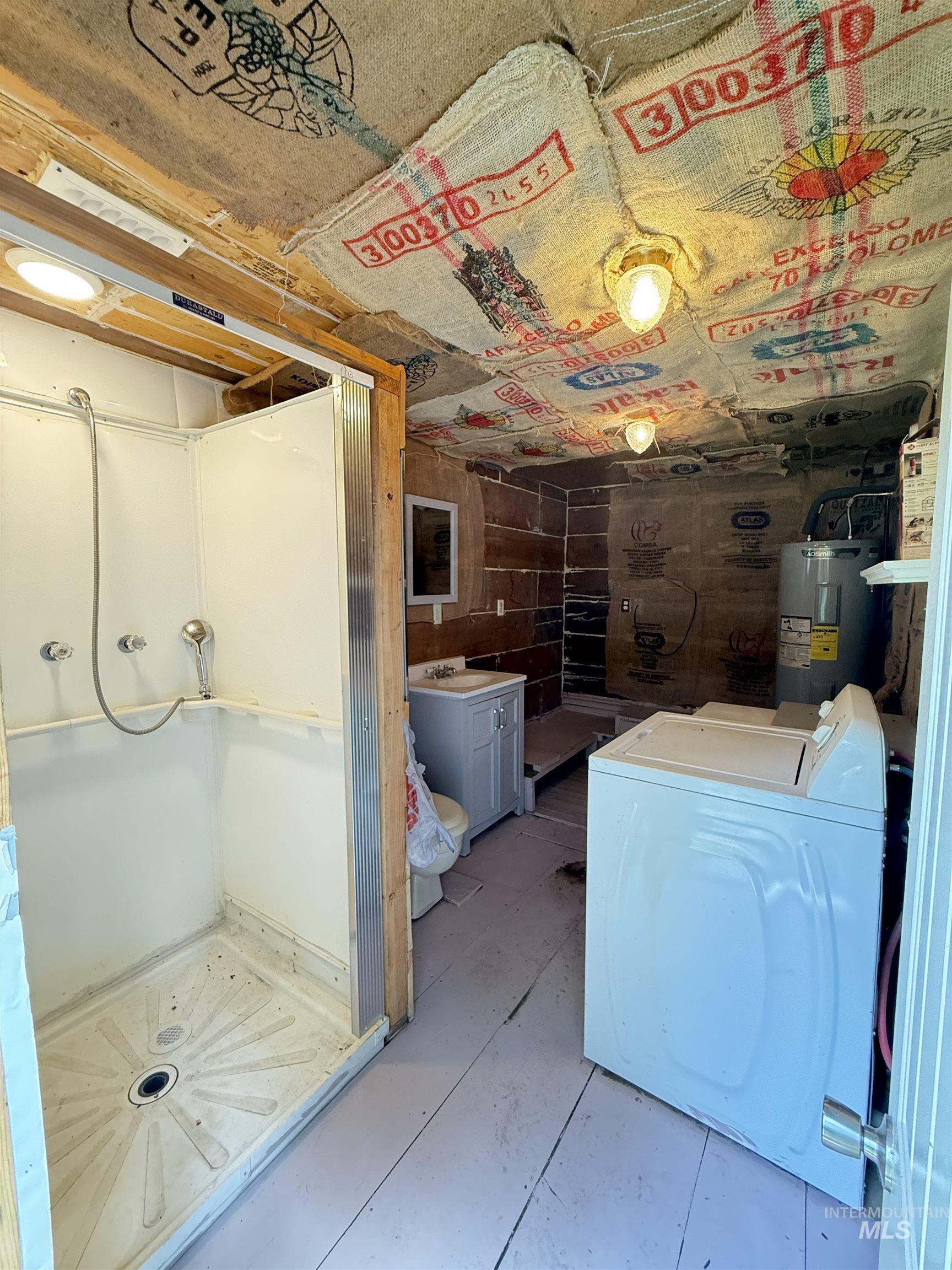 Full bathroom with washer / dryer, a stall shower, and water heater
