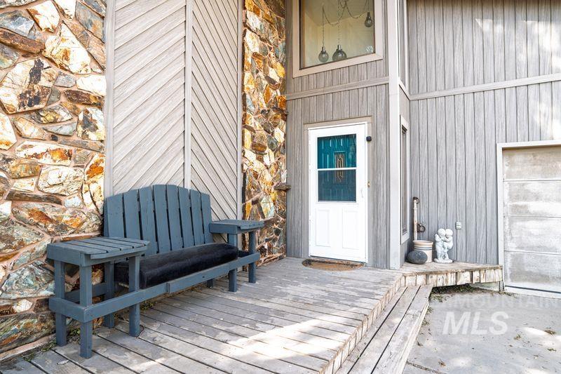 View of exterior entry featuring a deck and stone siding