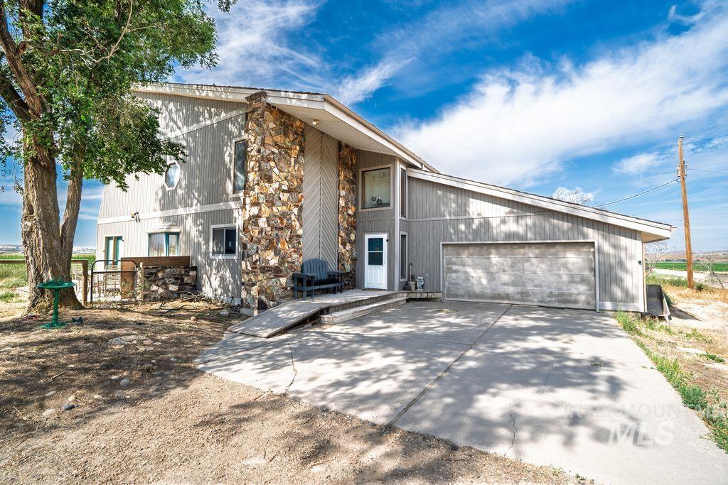 View of front of home with an attached garage, stone siding, and concrete driveway